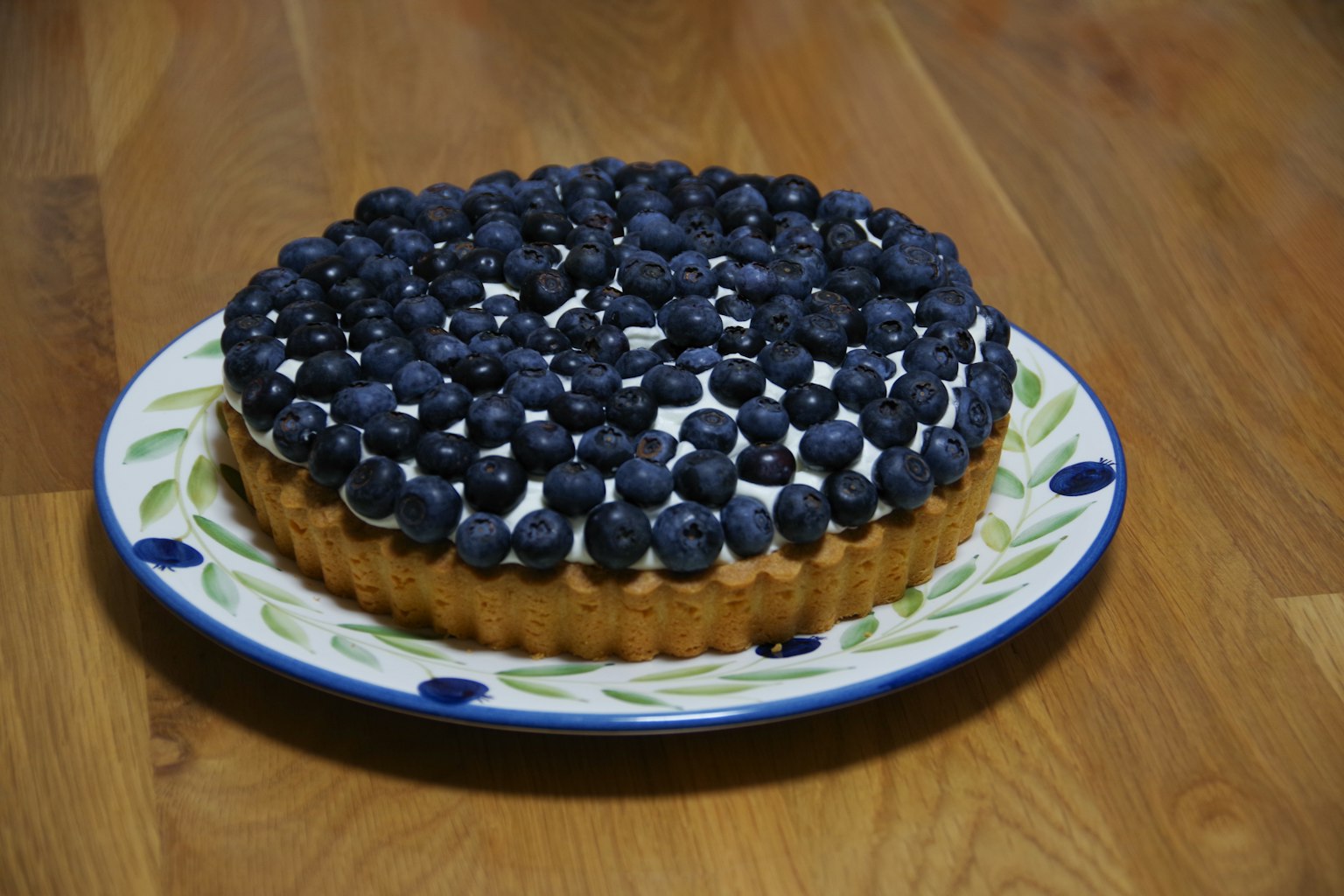 Crostata di mirtilli decorata con mirtilli freschi su un piatto decorativo