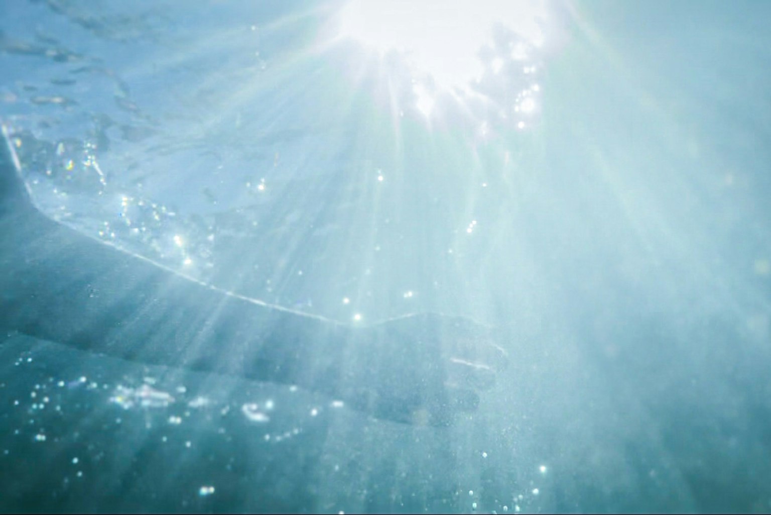 Une main s'étendant sous l'eau avec la lumière du soleil passant à travers