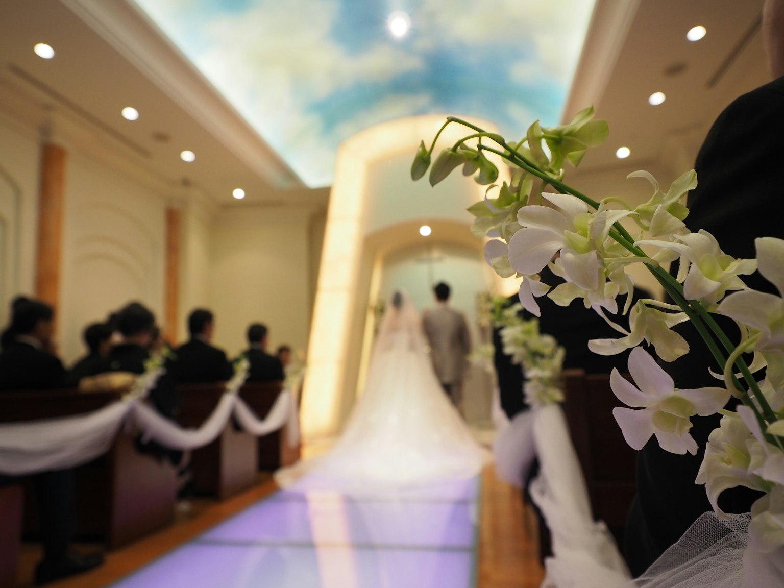 Image of a bride walking down the aisle in a wedding venue adorned with flowers and decorations