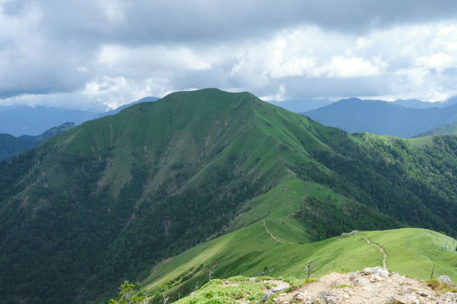 Vista panoramica di montagne verdi sotto un cielo nuvoloso