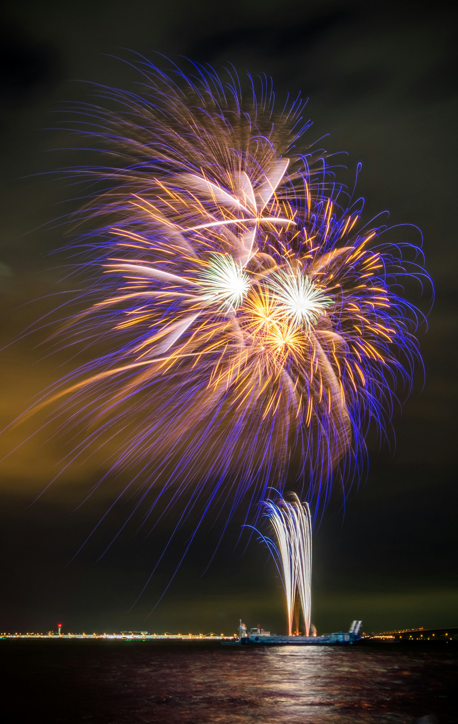 Espectáculo de fuegos artificiales vibrantes iluminando el cielo nocturno con reflejos en el agua