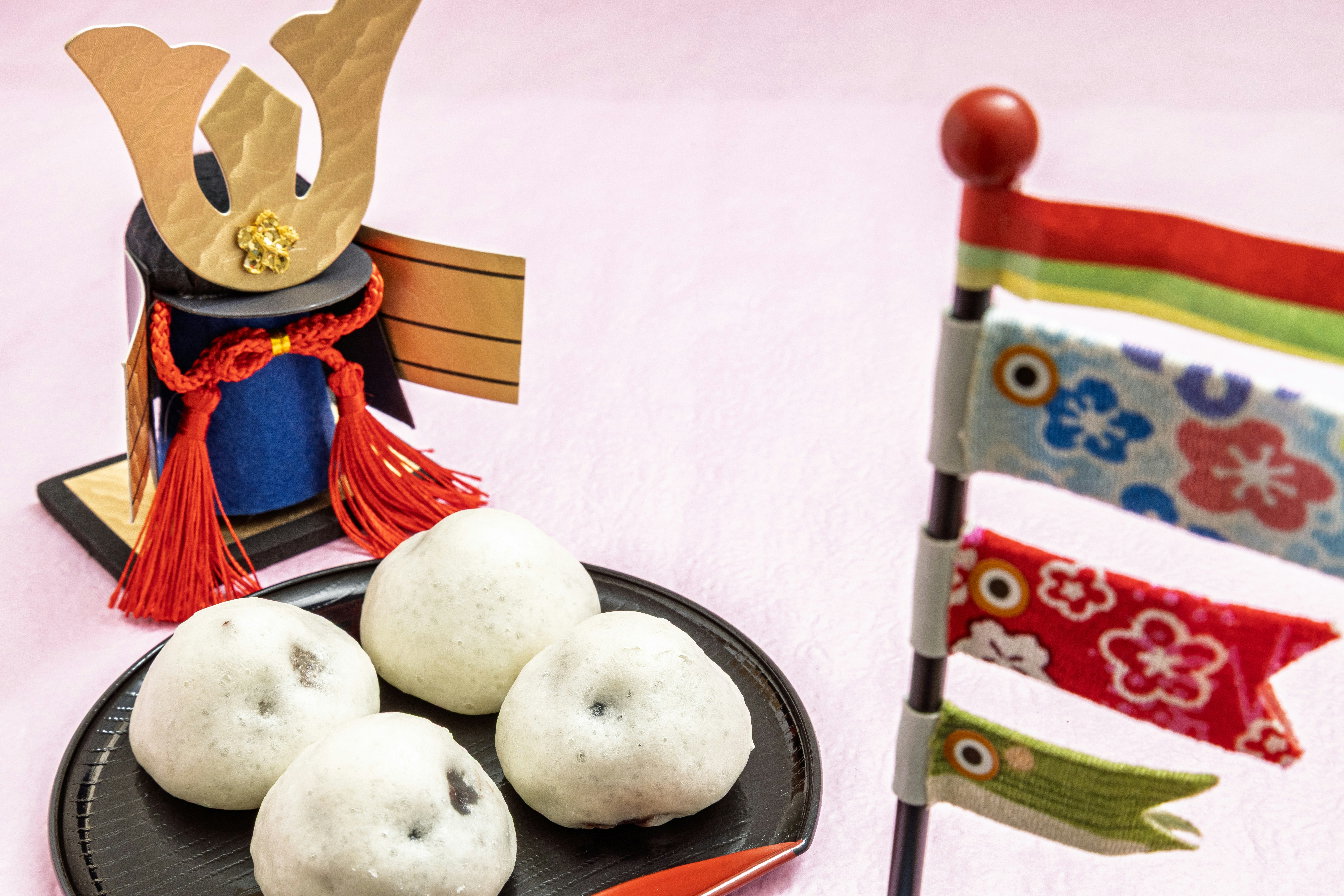 Tischdekoration mit Kabuto-Ornament, bunten Festfahnen und Reisbällchen