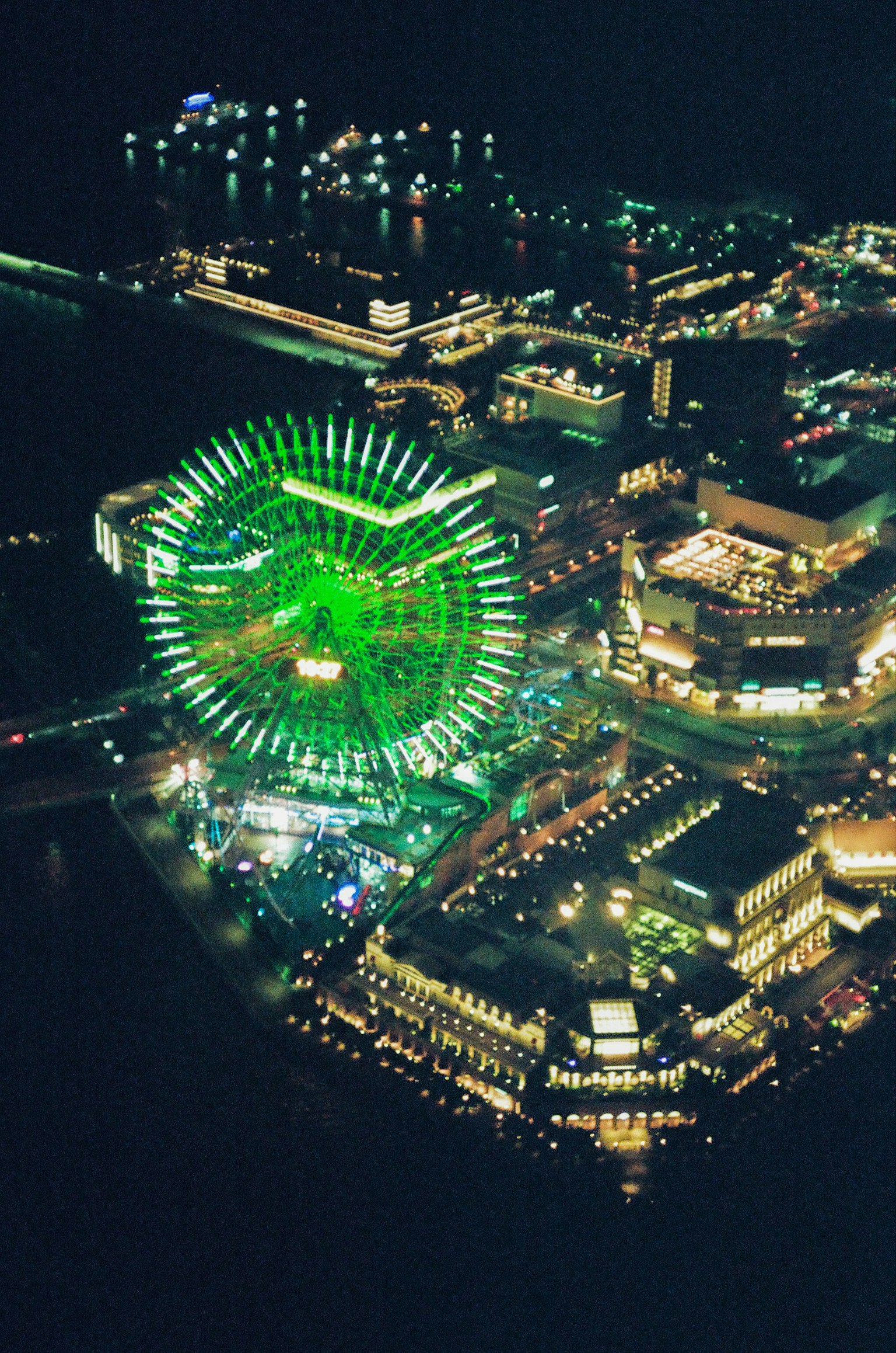 夜晚绿色照明摩天轮和周围建筑的鸟瞰图
