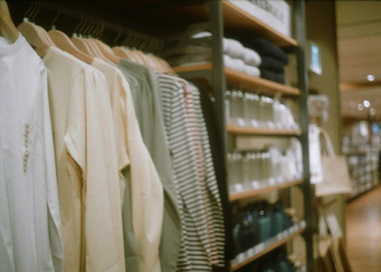 Clothes hanging on a rack with neatly arranged glassware displayed on shelves