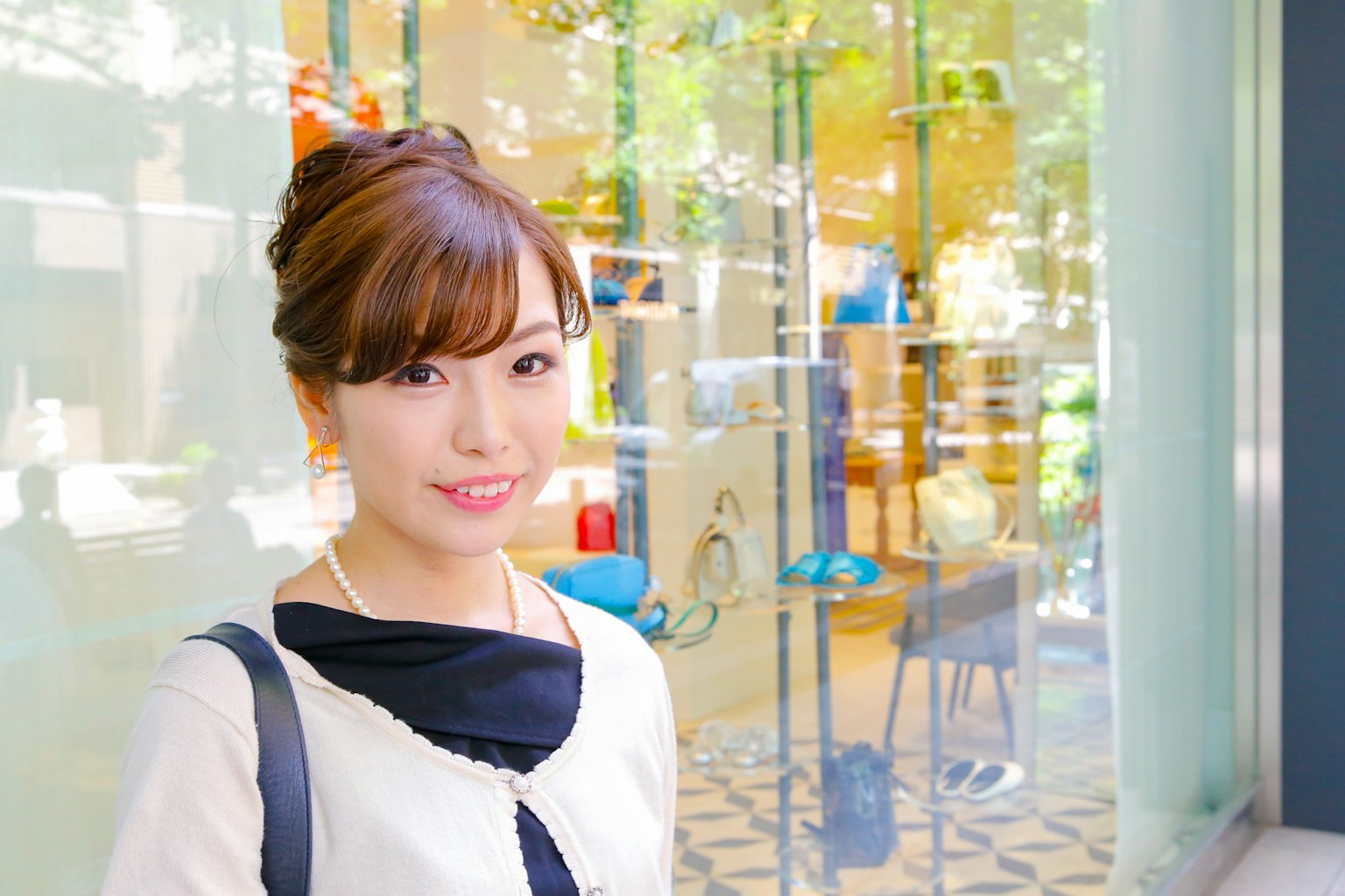 ผู้หญิงยิ้มในชุดทันสมัยยืนอยู่หน้าต่างโชว์ที่สว่าง