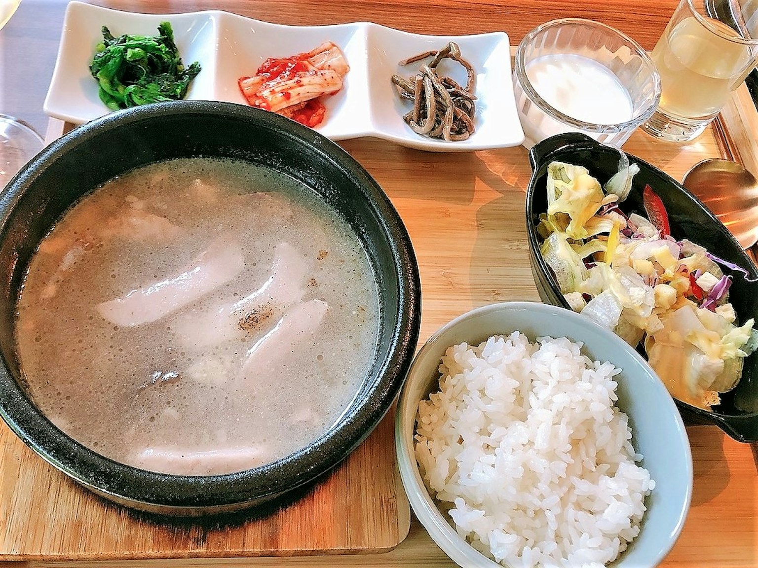 Un repas avec de la soupe, du riz blanc, une salade et des petits plats coréens