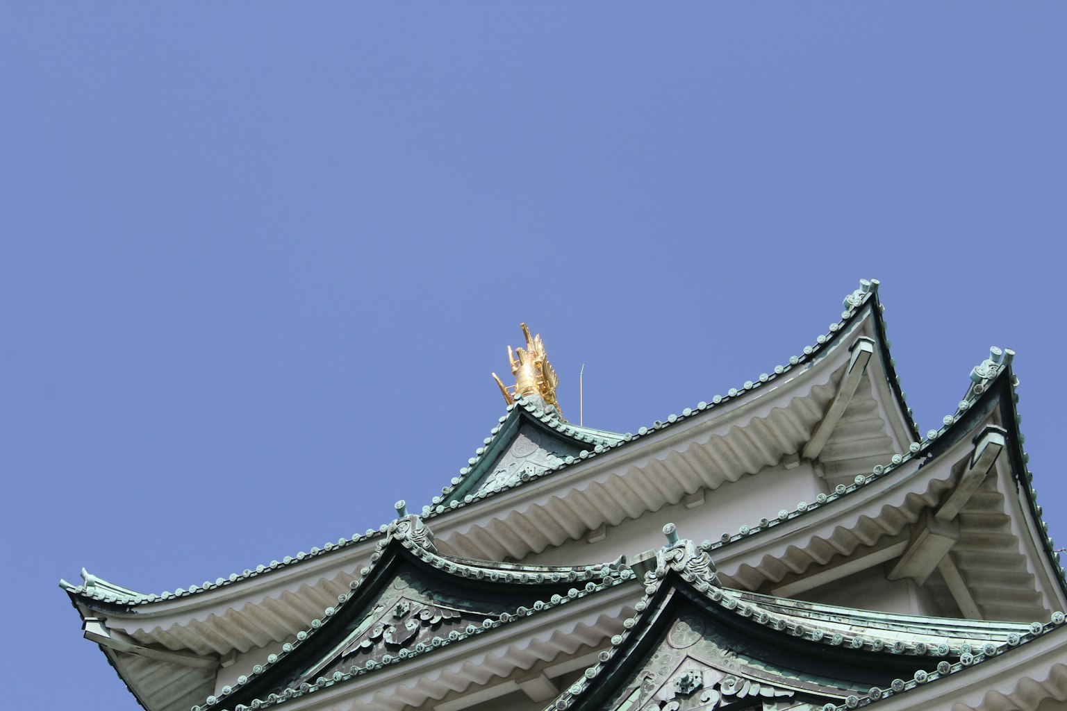 名古屋城的屋頂在晴朗的藍天下，帶有金色裝飾
