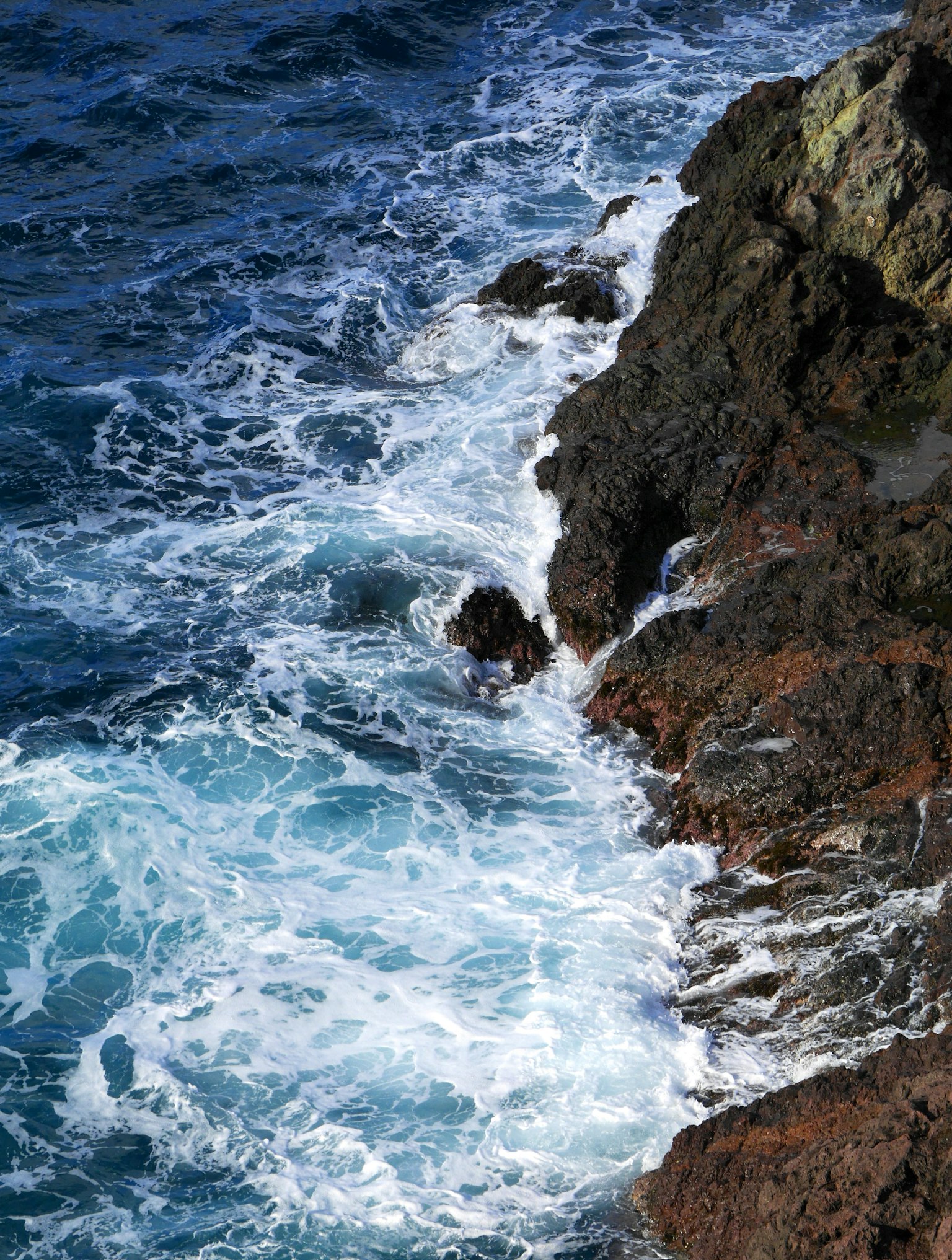 Vagues océaniques bleues s'écrasant contre une côte rocheuse