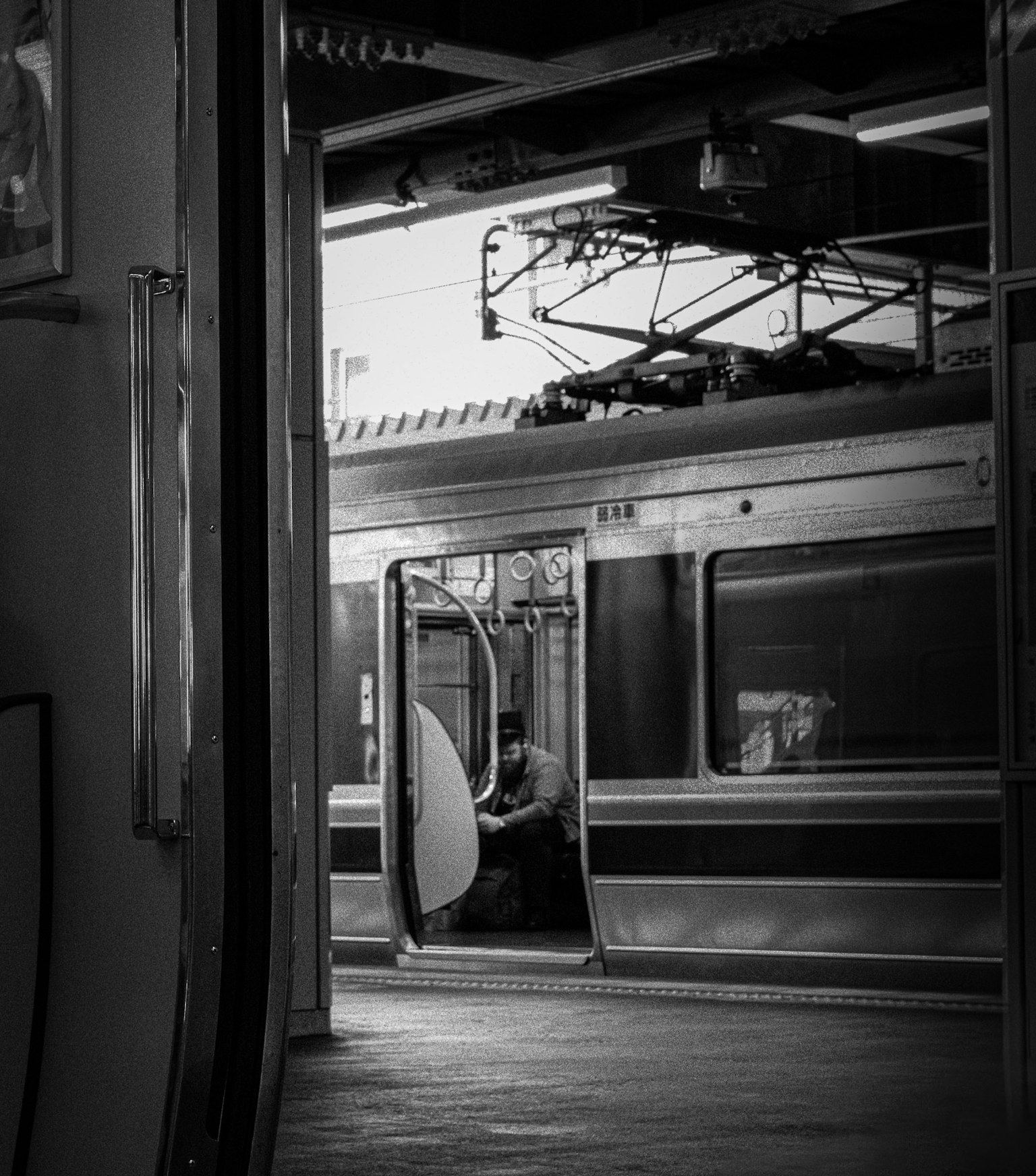 Foto hitam putih pintu kereta terbuka di platform stasiun