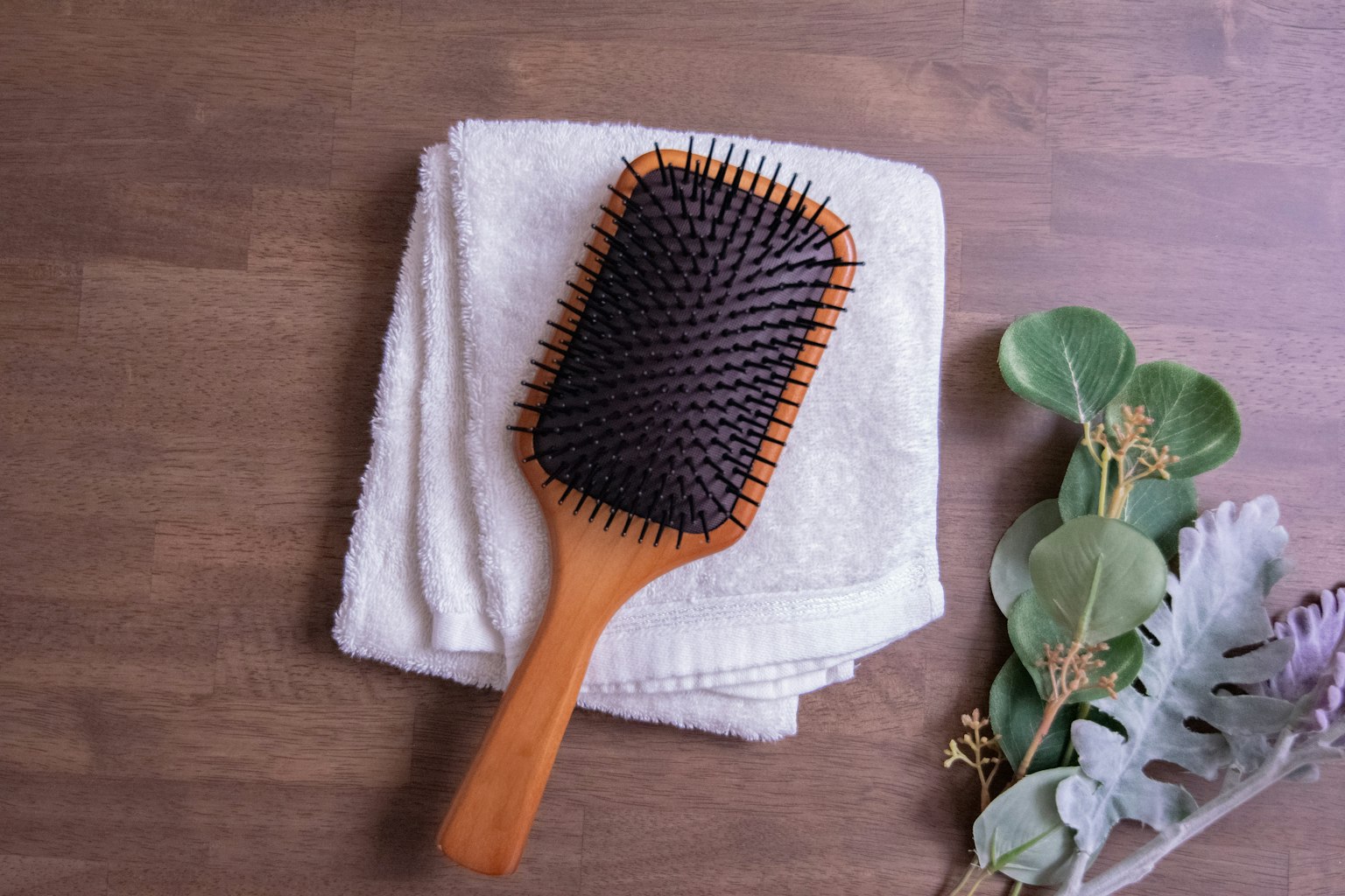 Sikat rambut kayu di atas handuk putih di permukaan kayu