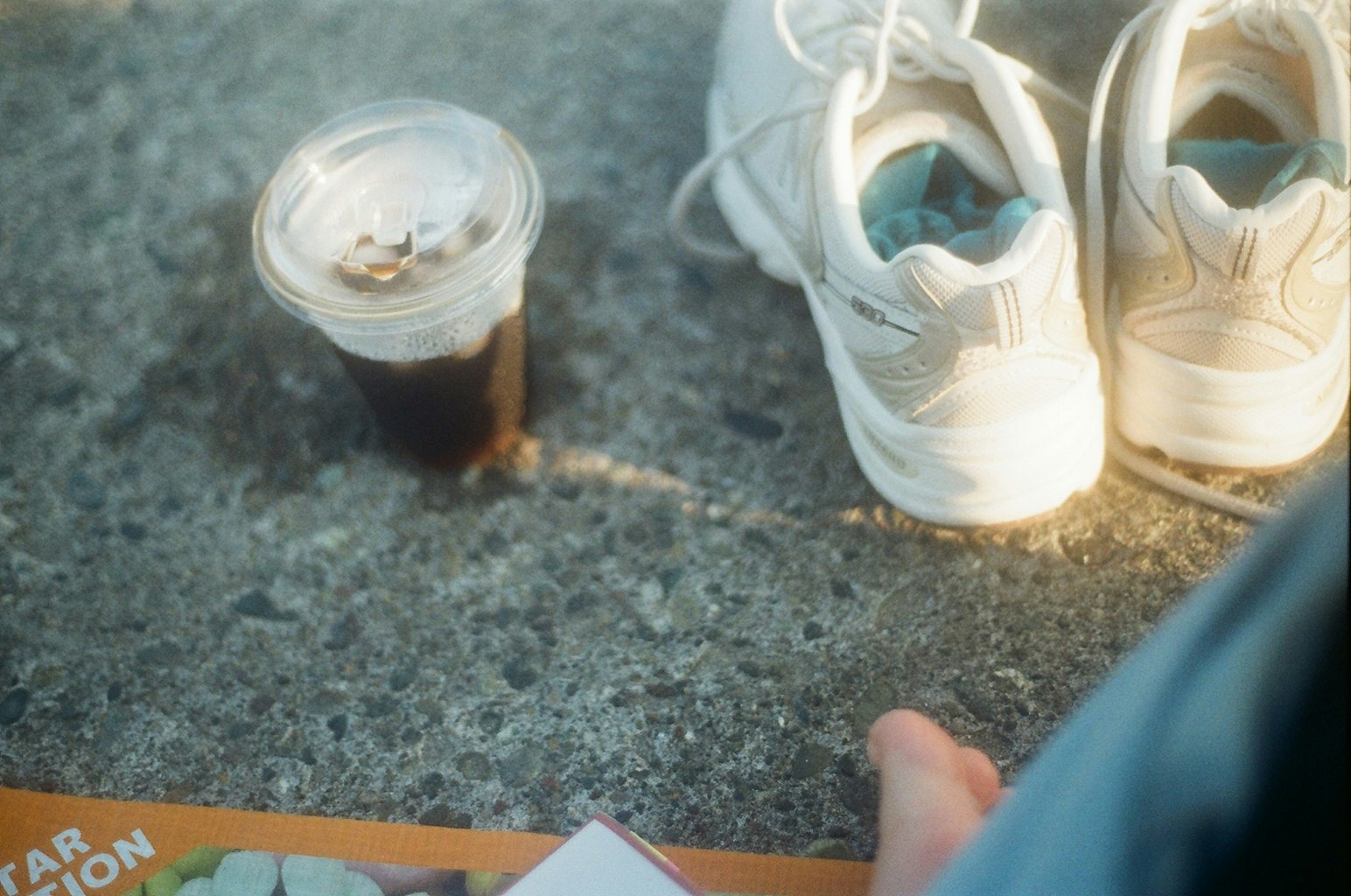 sneakers and a drink placed on a concrete floor