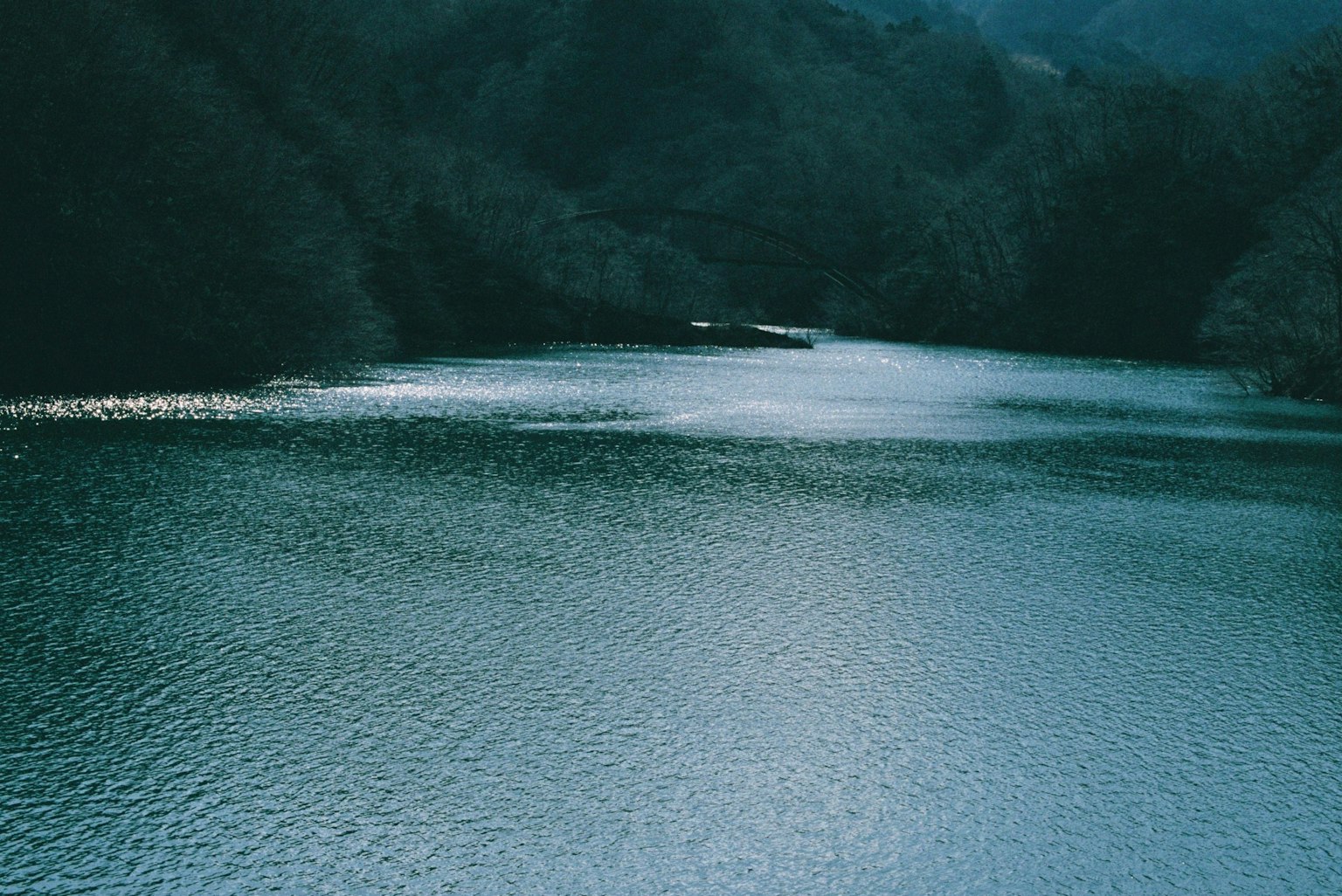 宁静的河流场景，周围环绕着绿色的水和山脉