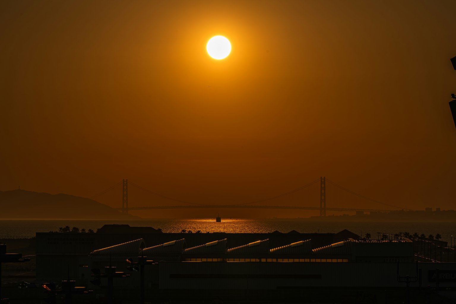 夕阳下建筑物的轮廓与海面上的落日