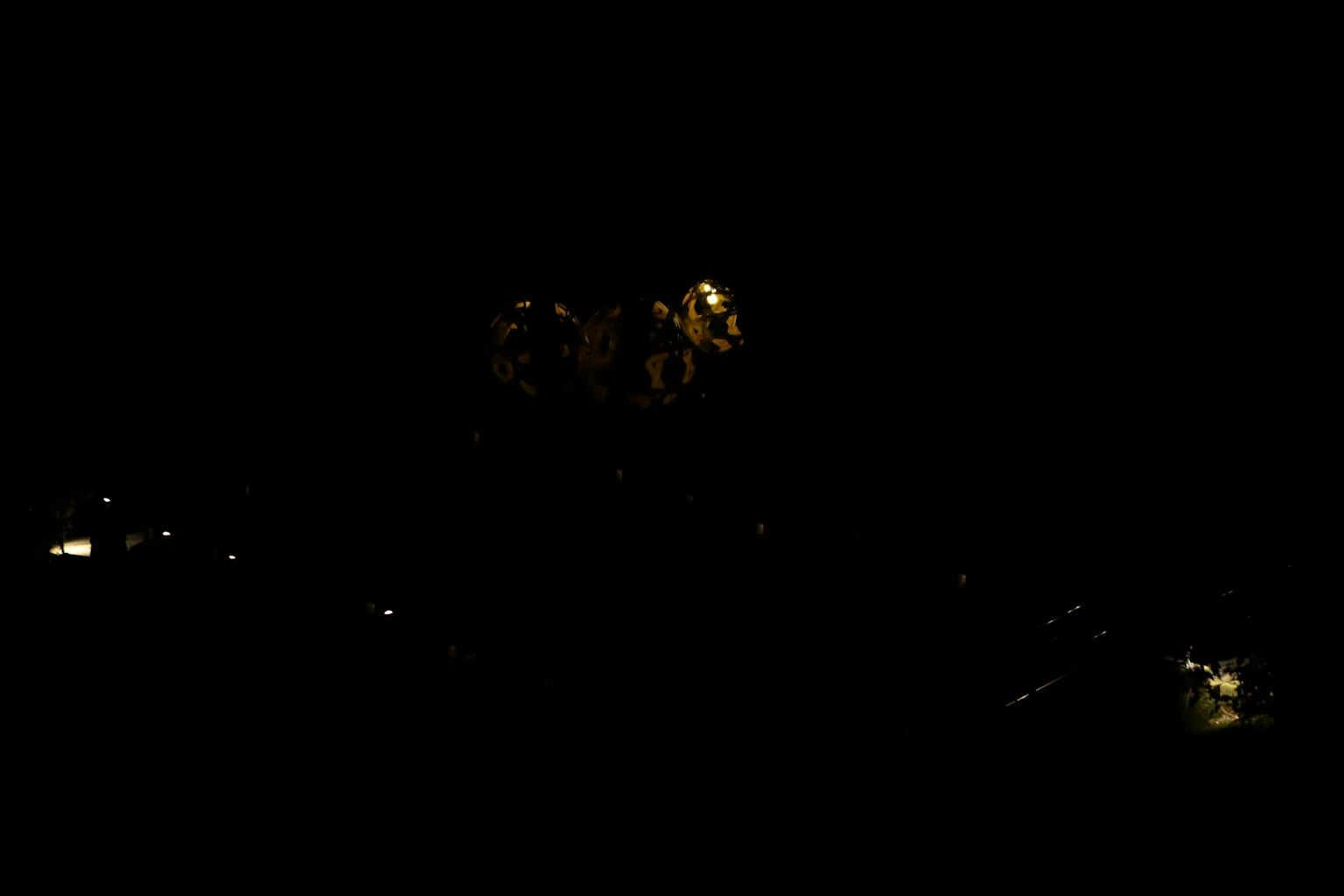 Nachtszene mit verstreuten hellen Lichtern und Farben vor einem dunklen Hintergrund