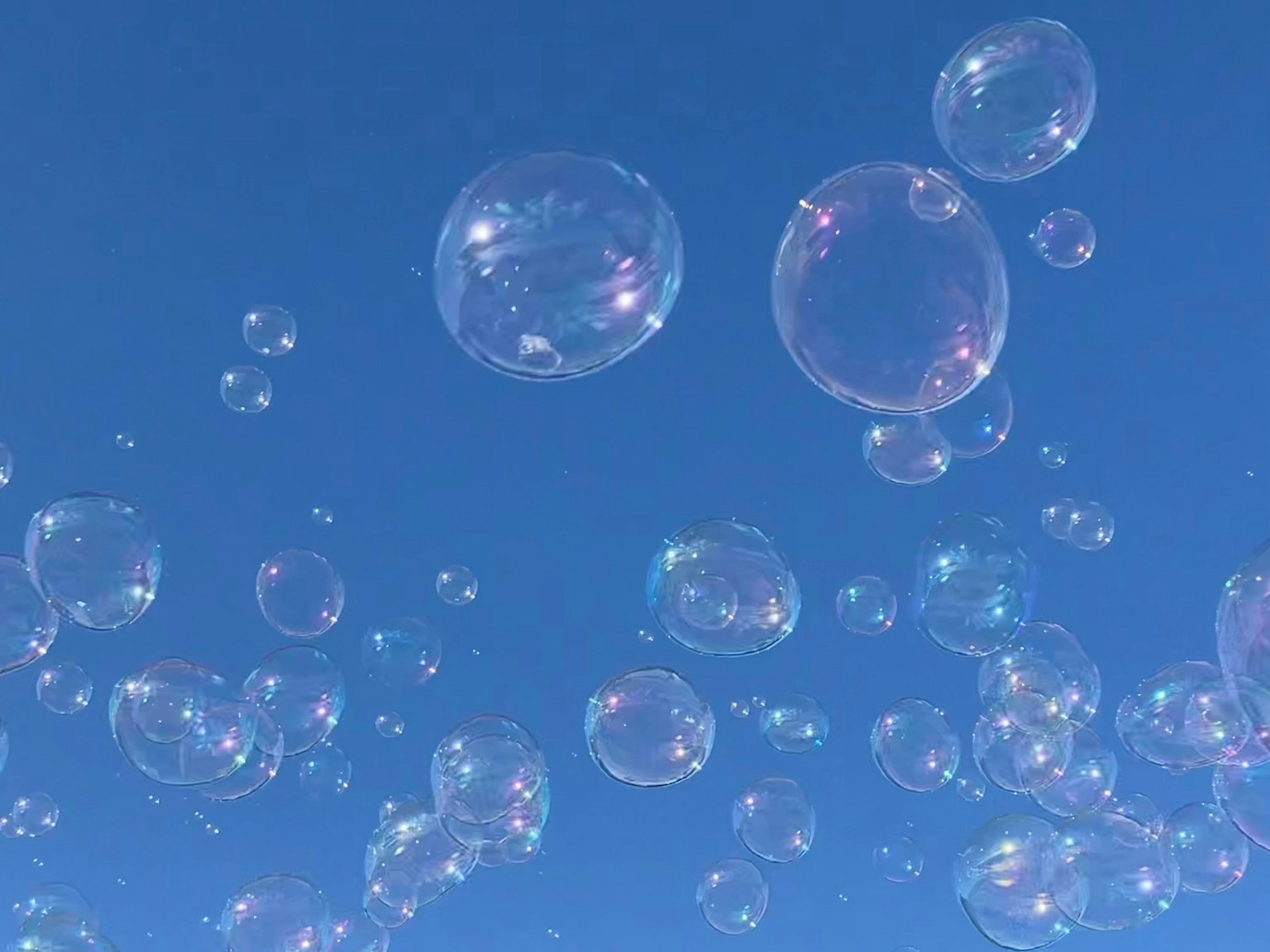 De nombreuses bulles de savon transparentes flottant dans un ciel bleu