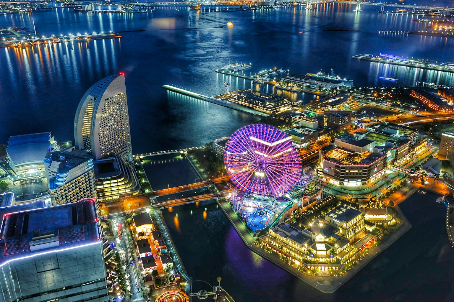 Vista nocturna de la bahía de Yokohama con una noria y luces de la ciudad