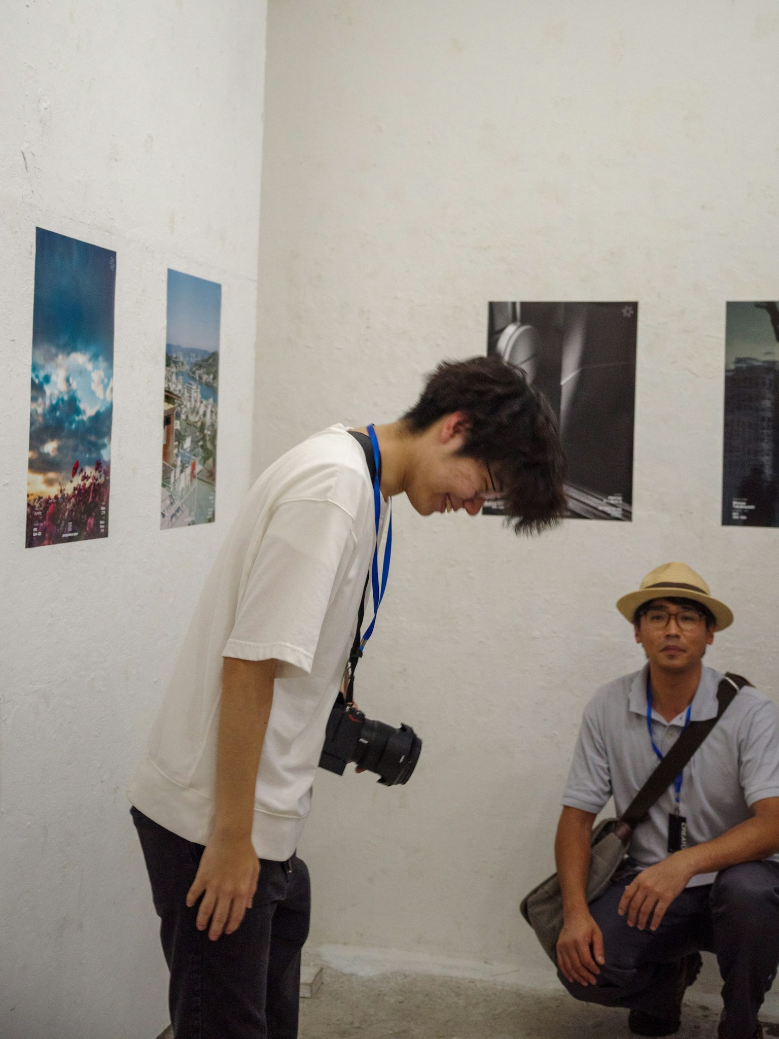 Two men observing photographs in a gallery with landscape images on the wall