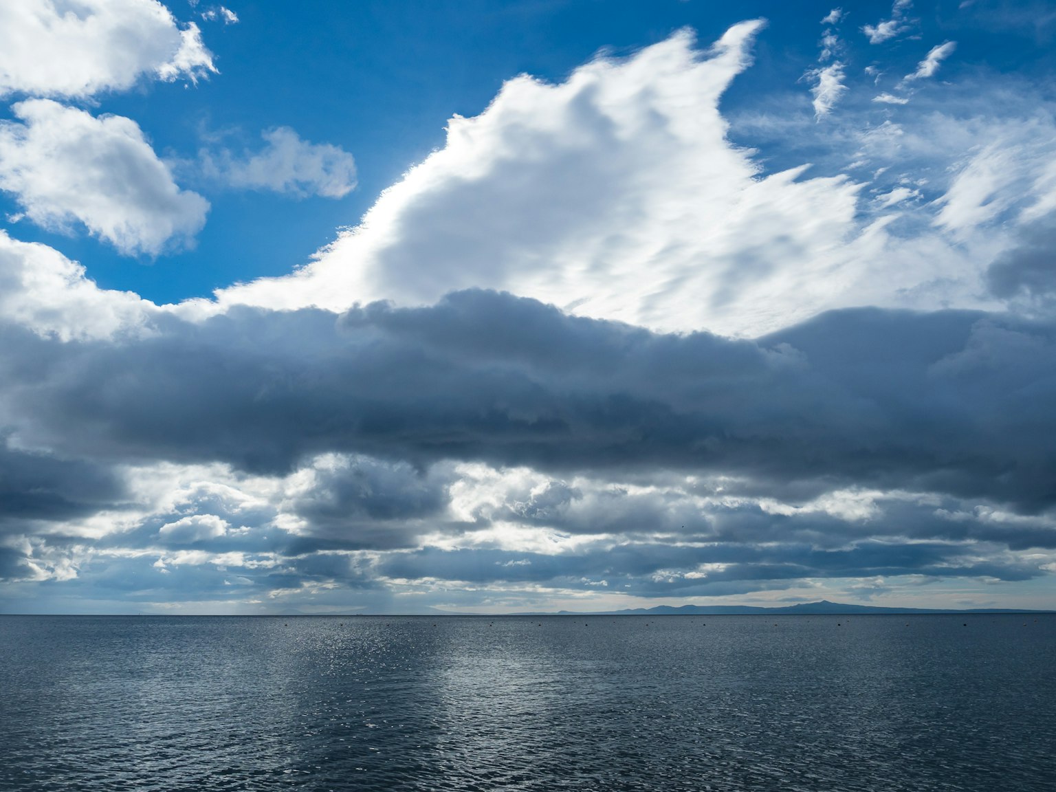 Ciel bleu avec des nuages blancs au-dessus d'une mer calme
