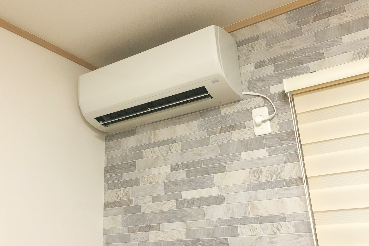 Un climatiseur blanc monté sur un mur gris dans un coin de la pièce