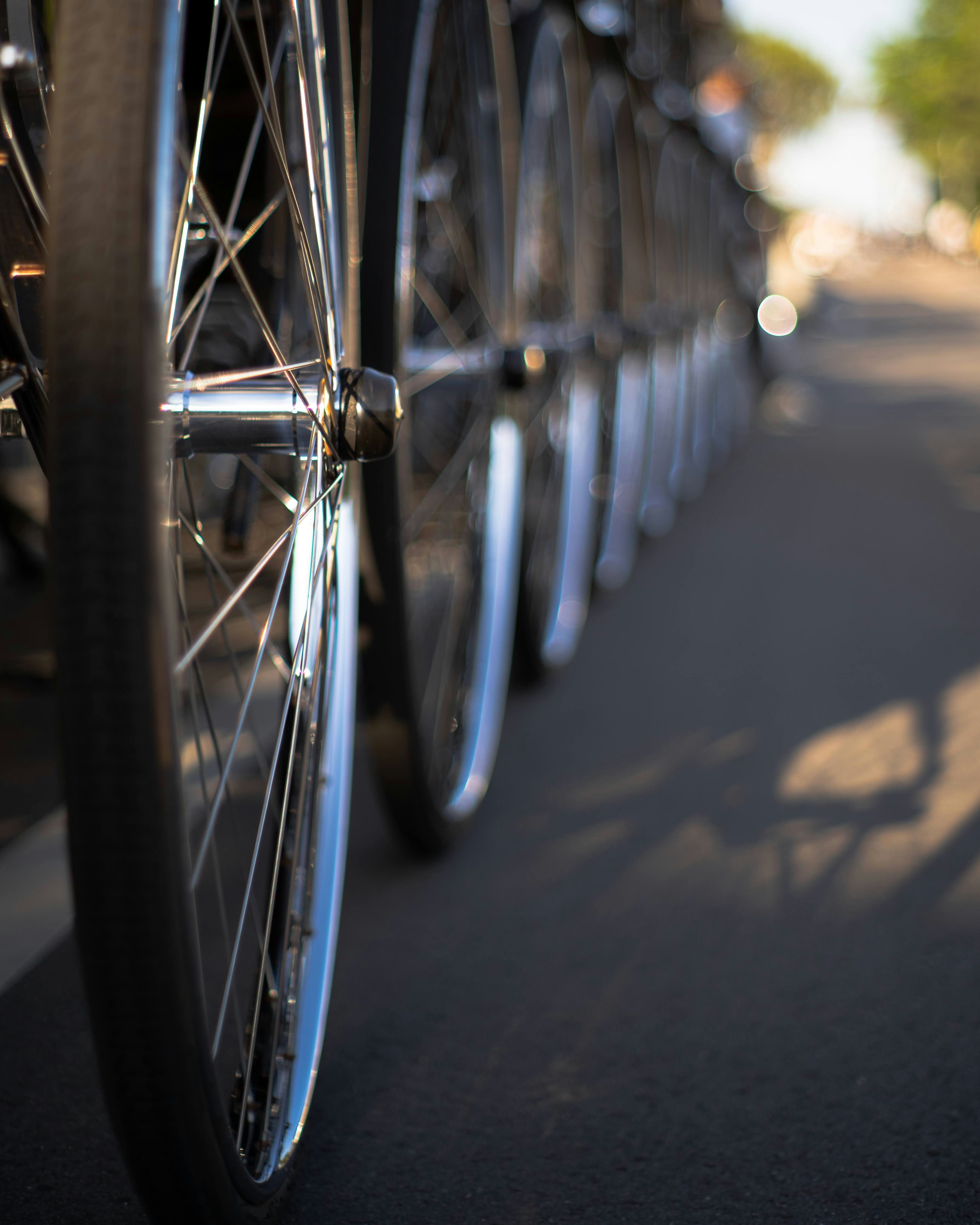 front wheels and spokes of bicycles lined up on a street