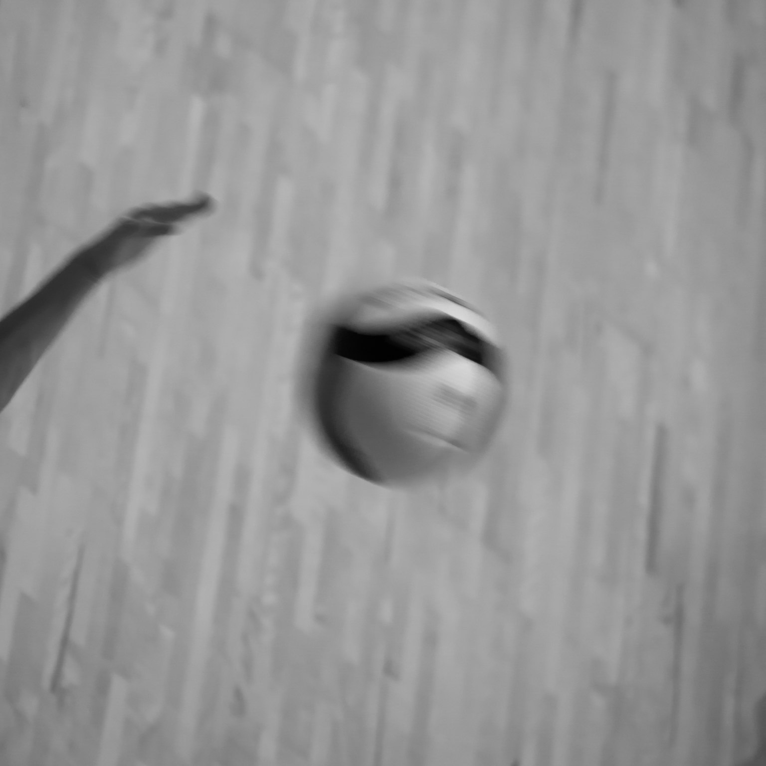 Sebuah tangan yang siap melempar bola sepak dengan latar belakang lantai kayu