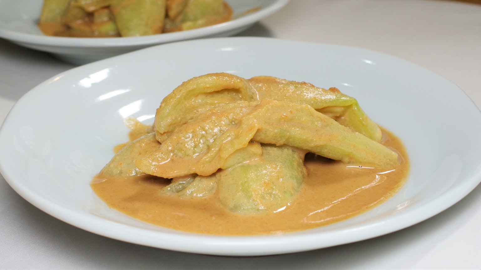 Dumplings covered in creamy sauce served on a white plate