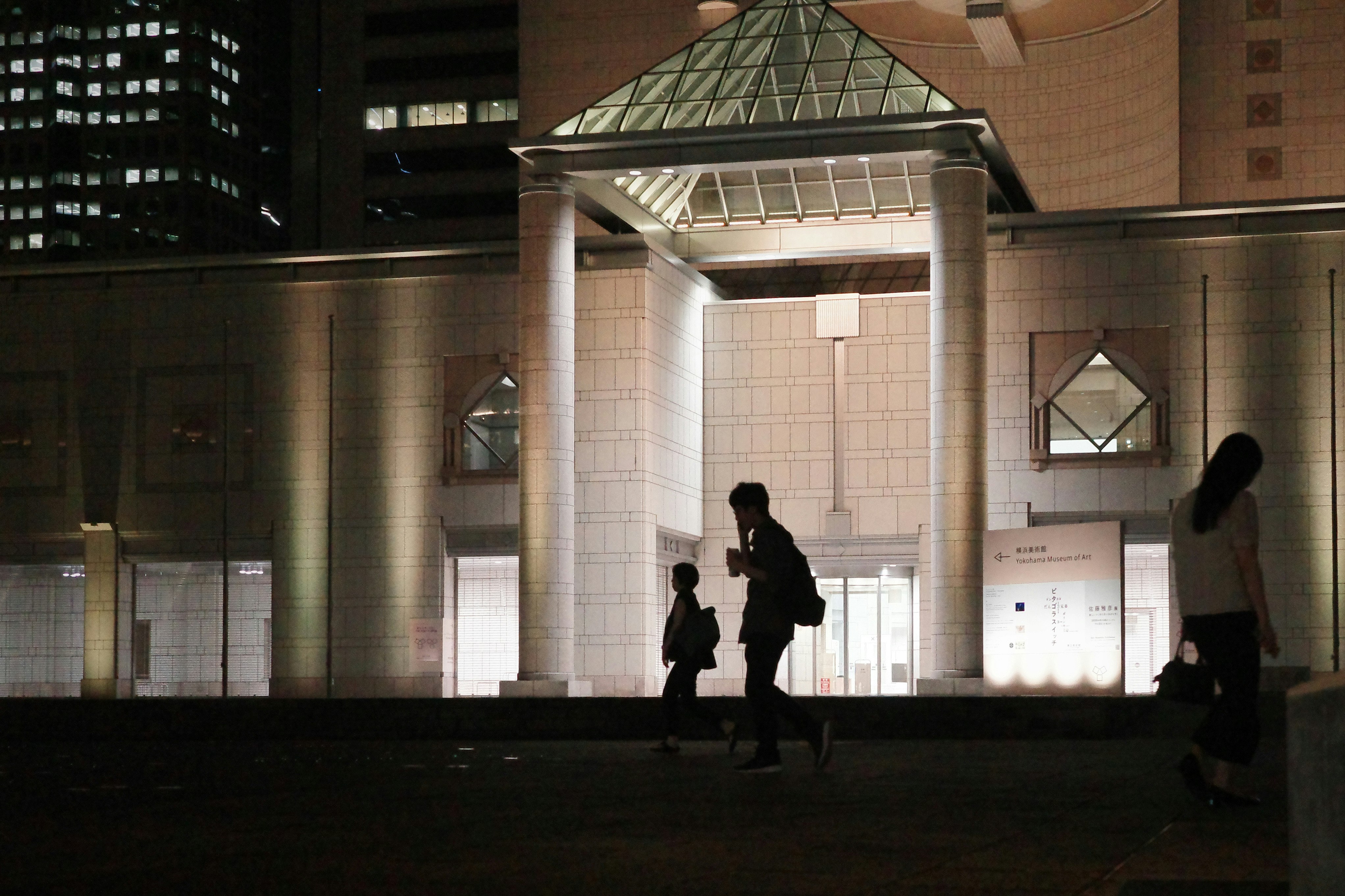夜の駅構内でシルエットの人が行き交う通路