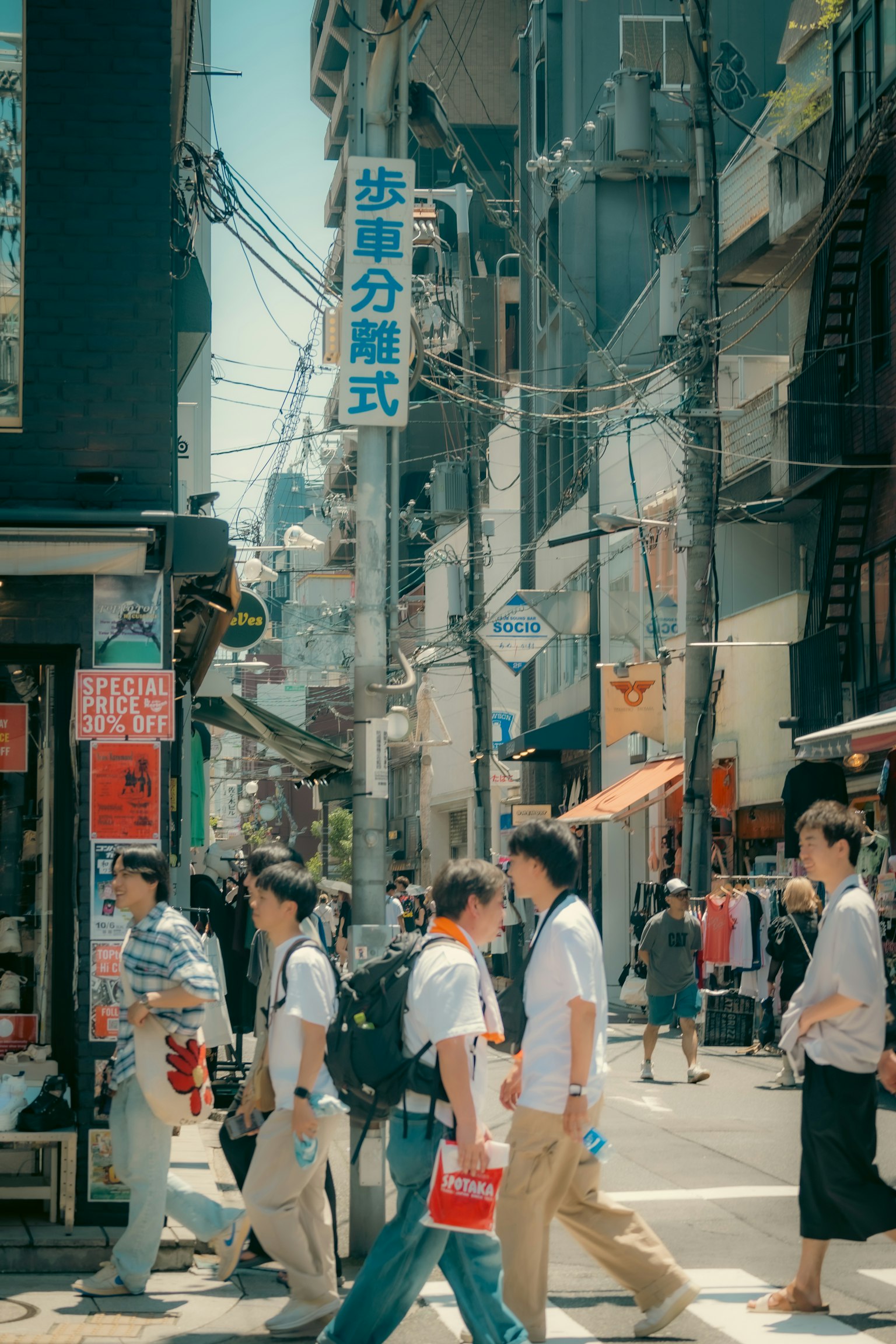 ฉากถนนที่พลุกพล่านในโตเกียวมีผู้คนเดินและร้านค้าตลอดแนวถนน