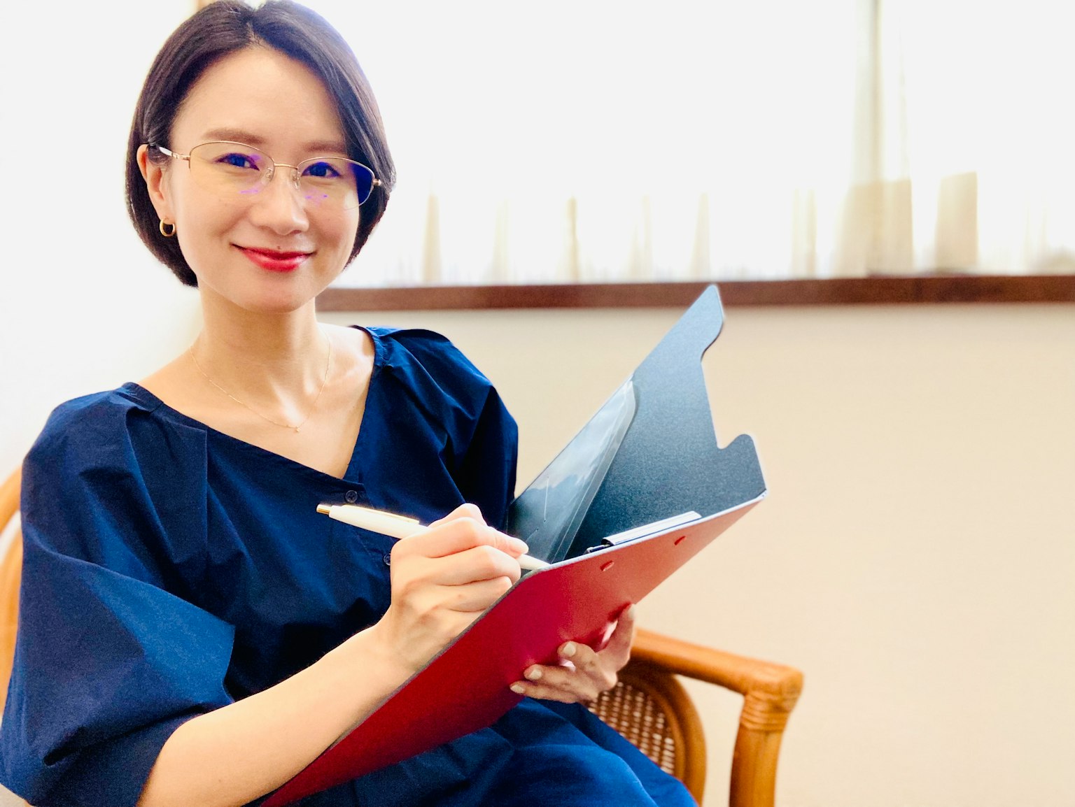 Una mujer con un vestido azul escribiendo en un cuaderno
