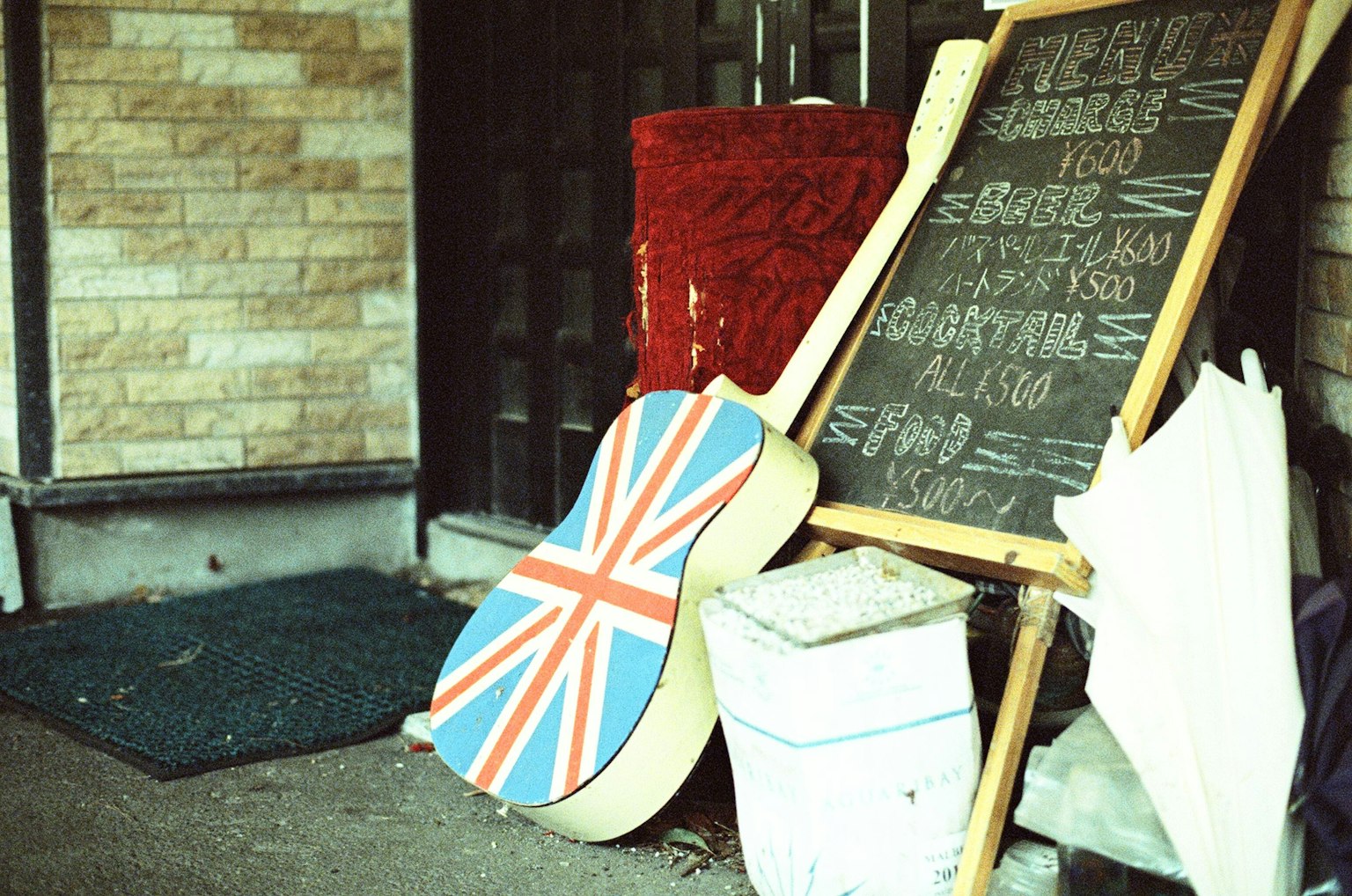 Guitarra con diseño de la bandera británica al lado de una pizarra y un tejido rojo