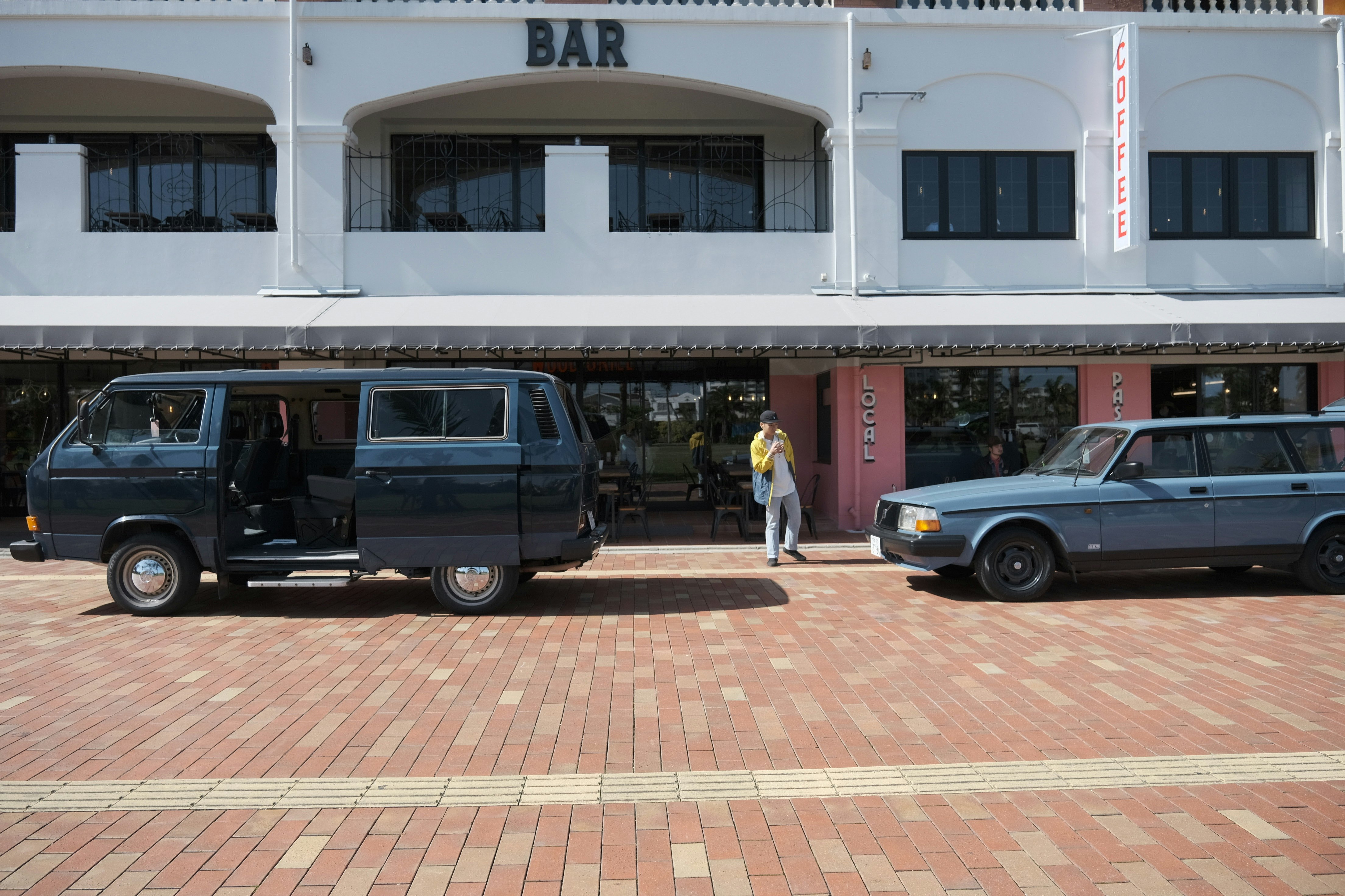 「BAR」看板のある建物前に並ぶクラシックなバンと車