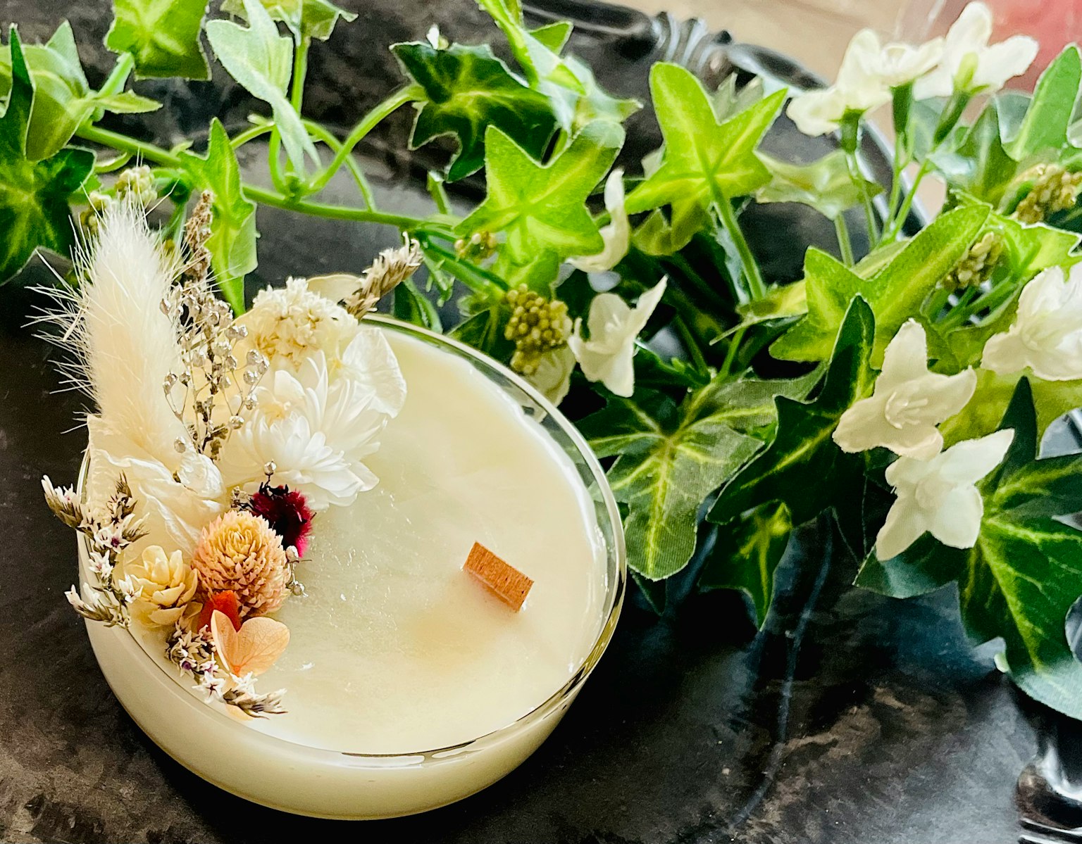 A decorative candle adorned with flowers and natural elements