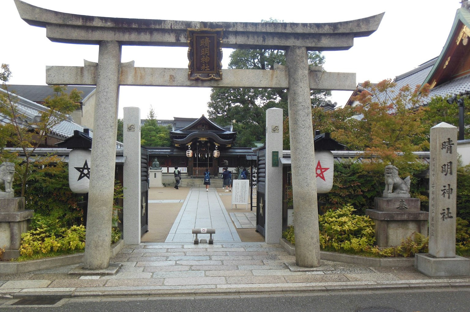 Ansicht des Eingangs eines Schreins mit einem Torii und Steingartenlaternen