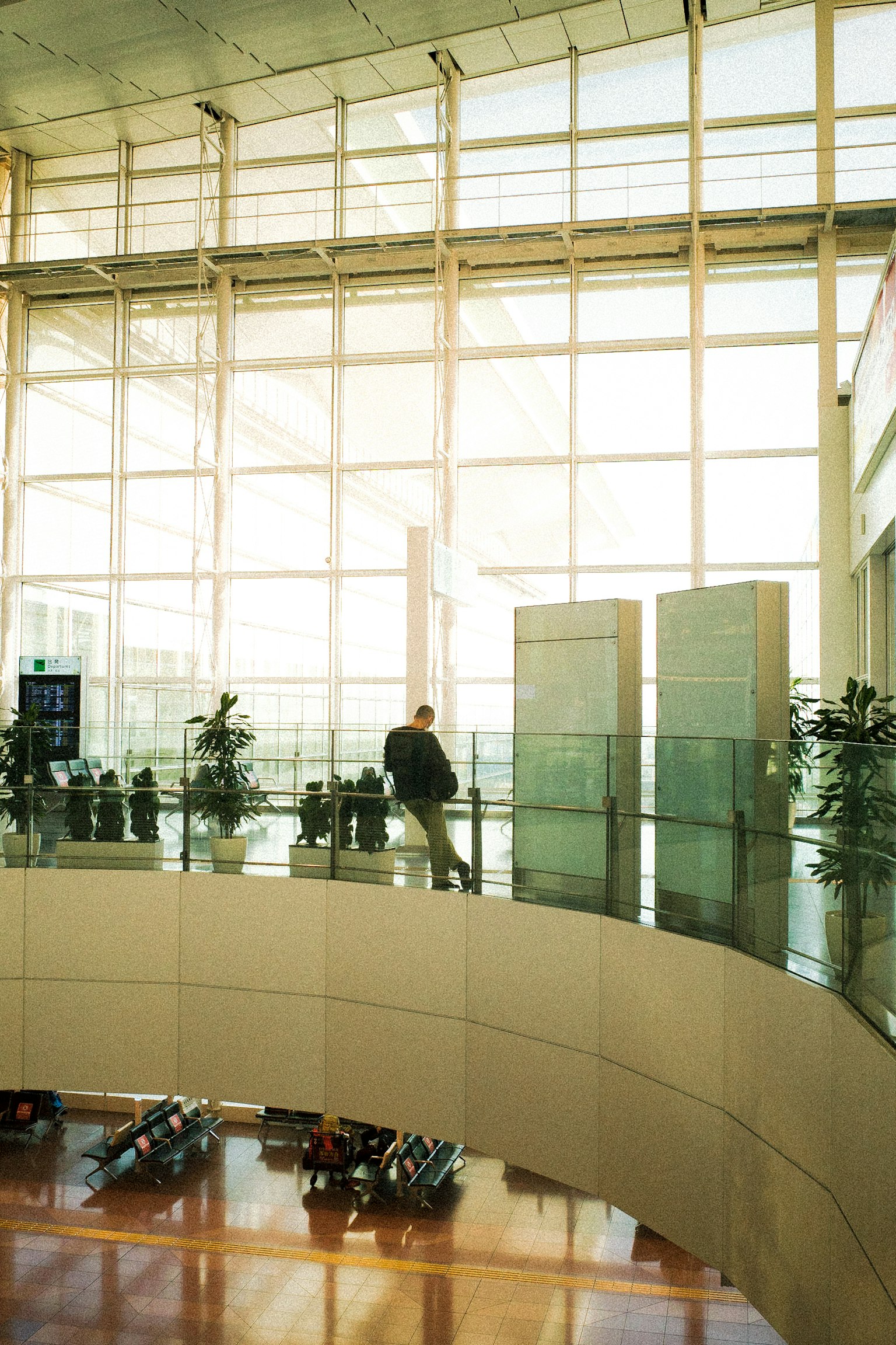 Una persona de pie en el interior de un aeropuerto moderno con paredes de vidrio brillante