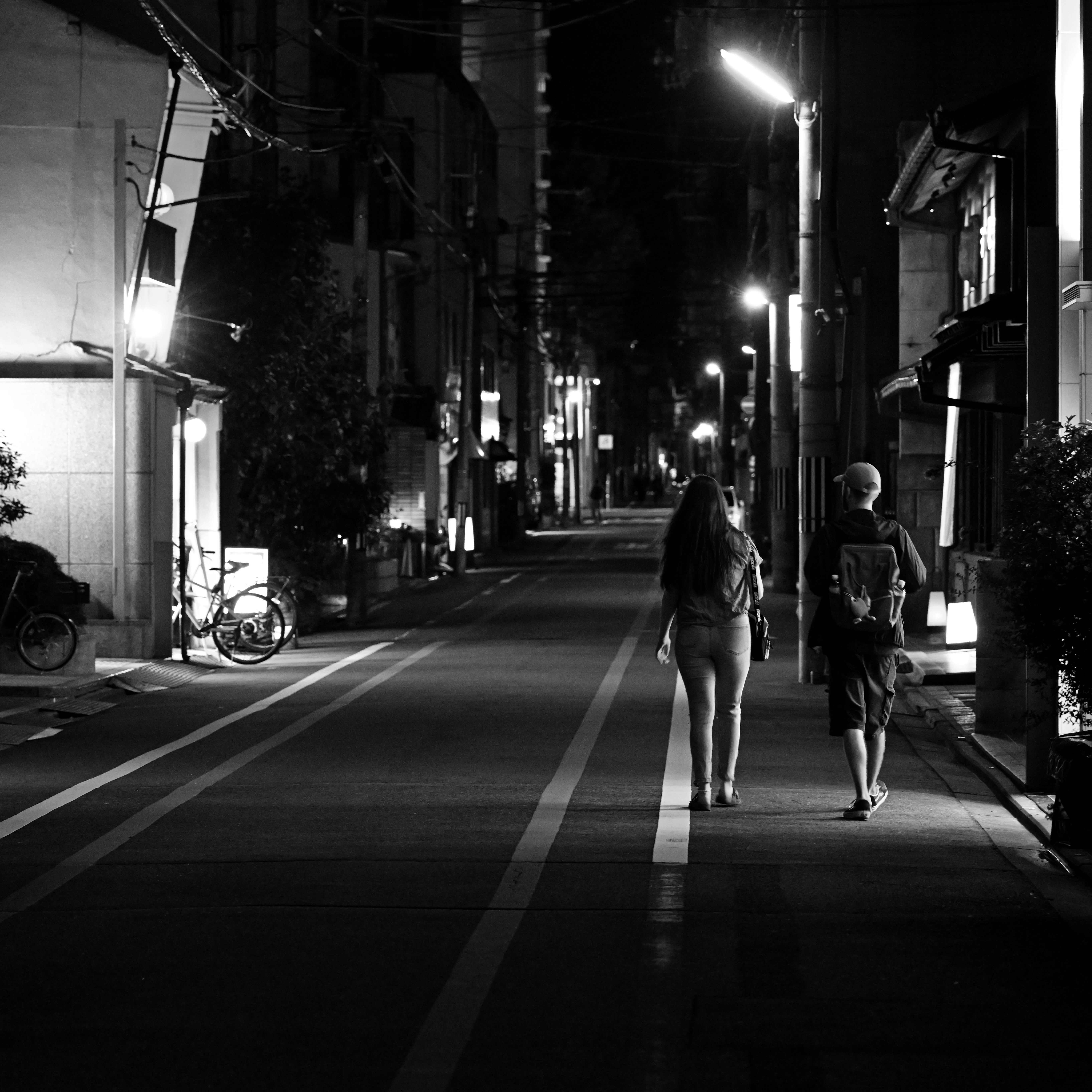 夜の京都の裏通りを歩くふたりのシルエットのあるモノクロ路地