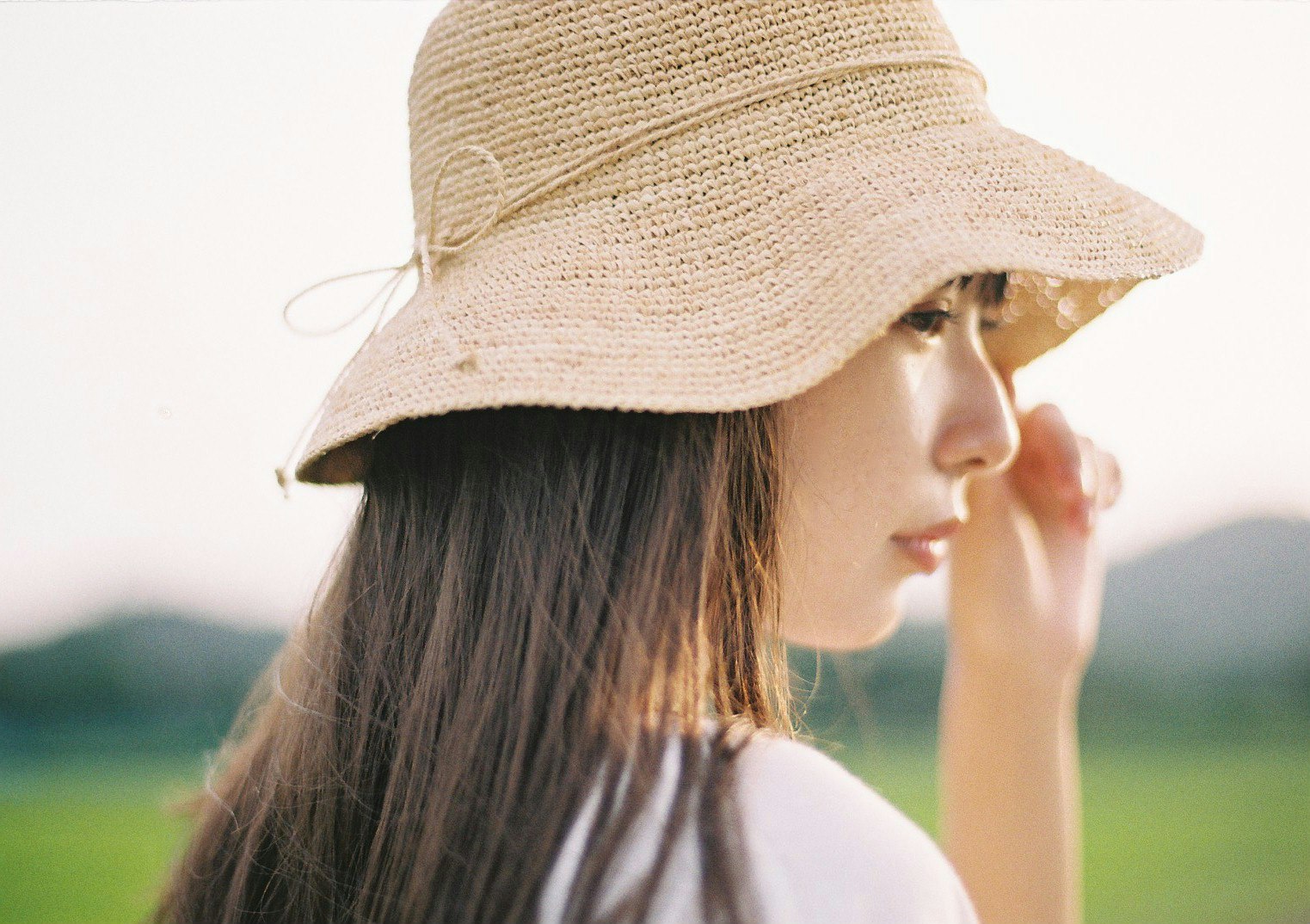 side profile of a woman wearing a straw hat