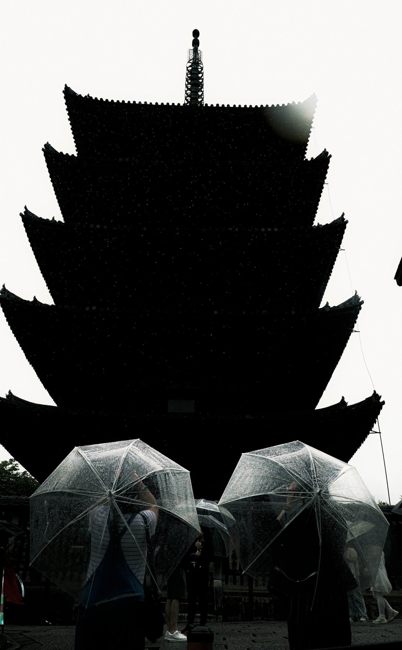 Silhouette d'une pagode avec des personnes tenant des parapluies transparents par un jour de pluie