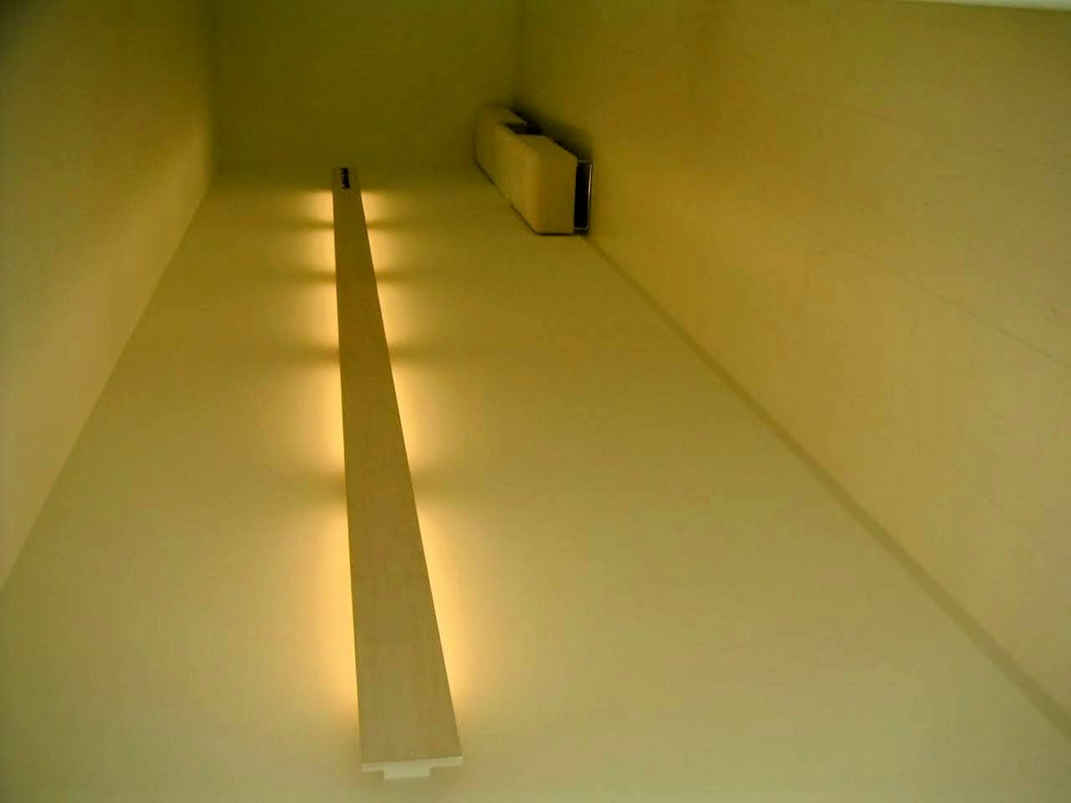 A room with bright walls and floor featuring a long light fixture