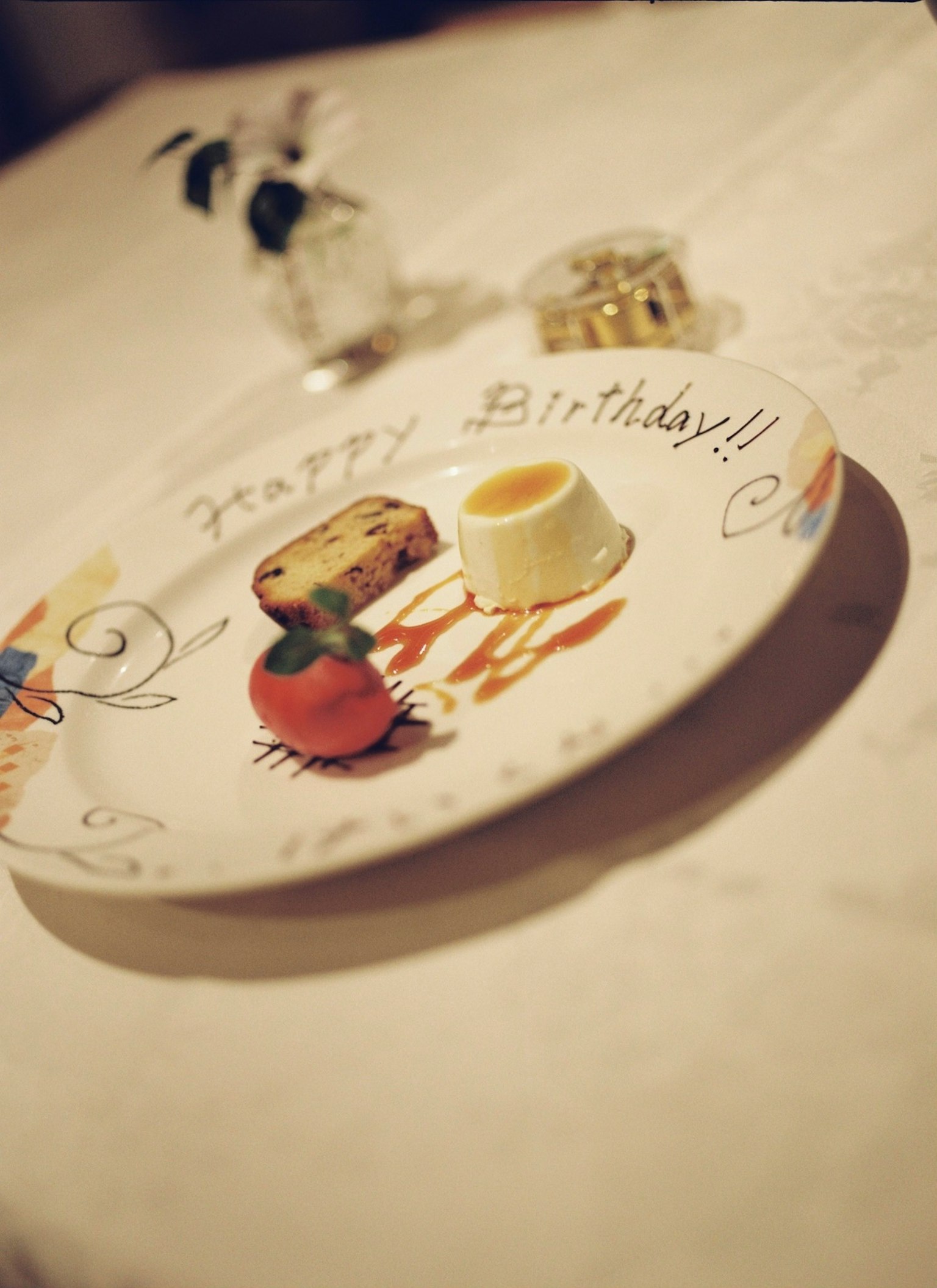 Un piatto di compleanno con un dessert e frutta, con un messaggio scritto a mano