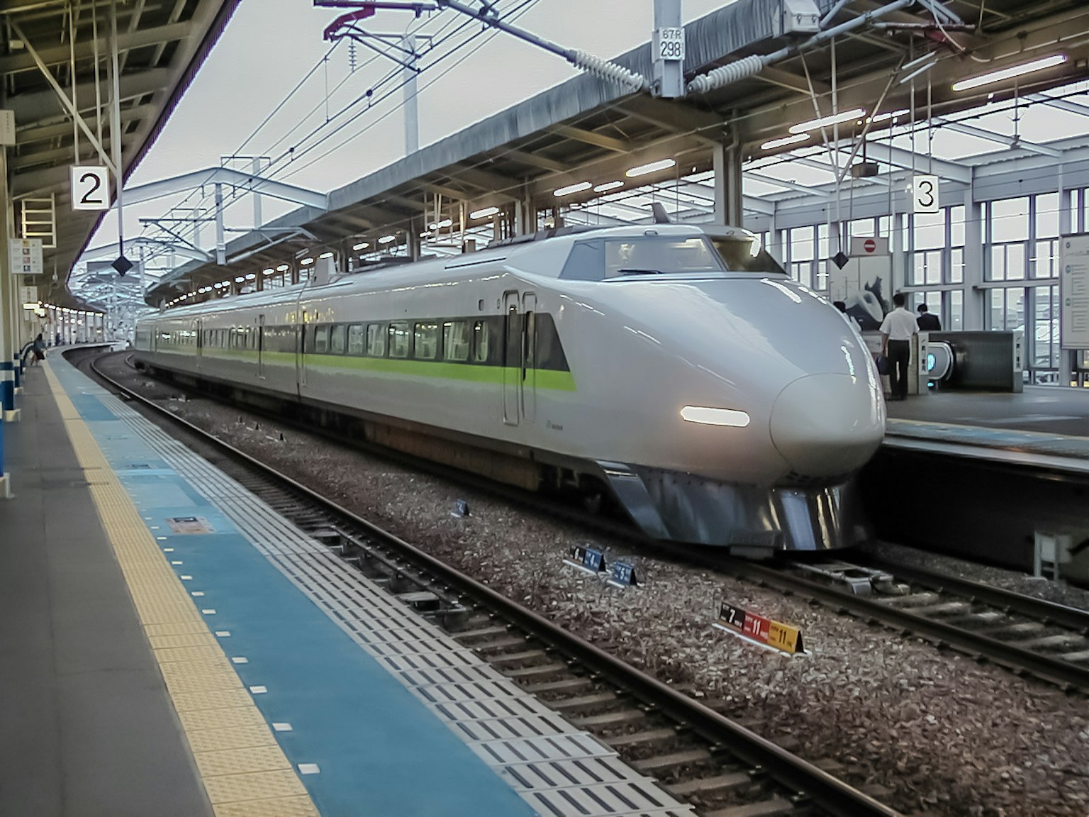 Shinkansen train stopped at a station featuring a modern design and silver exterior