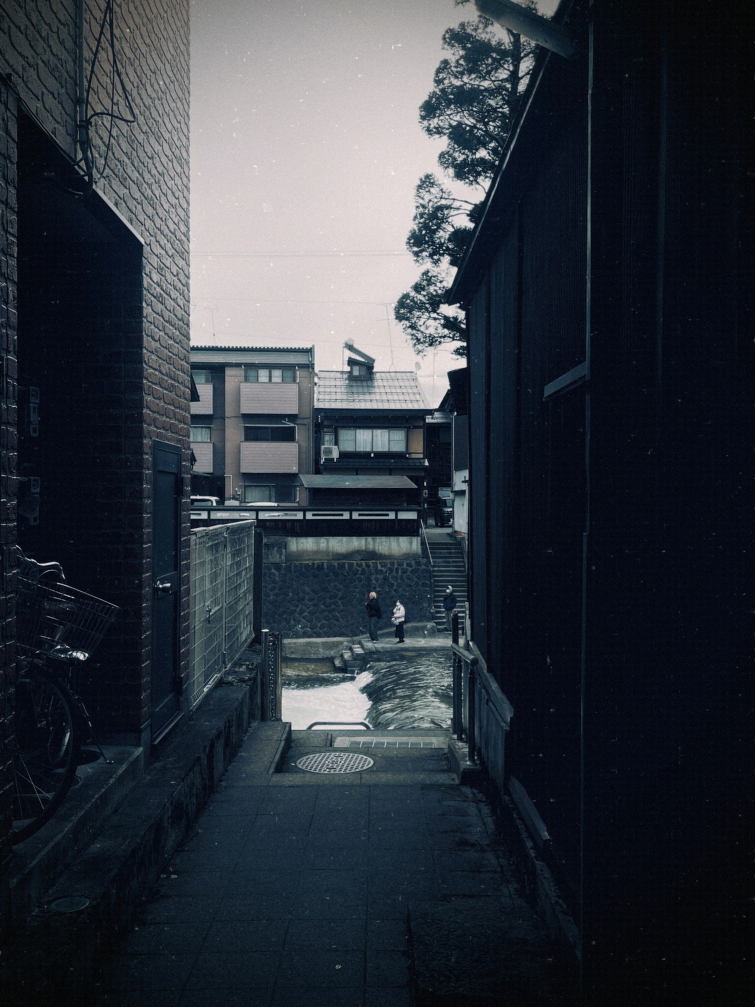 狭い路地に沿った建物と水たまりが見える風景