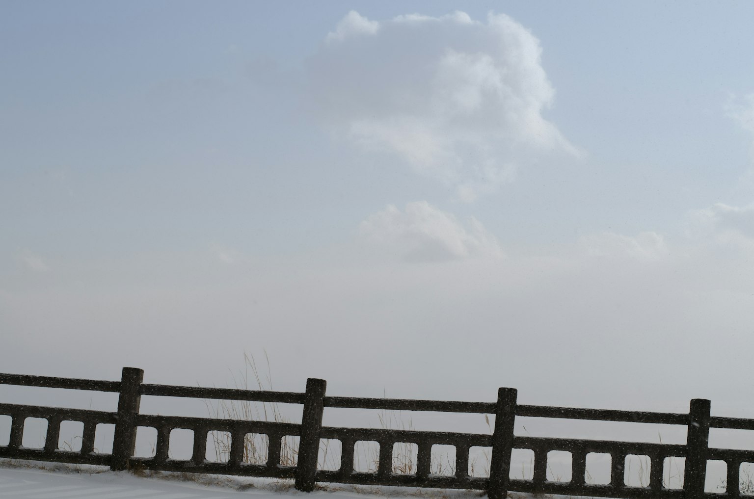 Clouds in a blue sky above a concrete fence