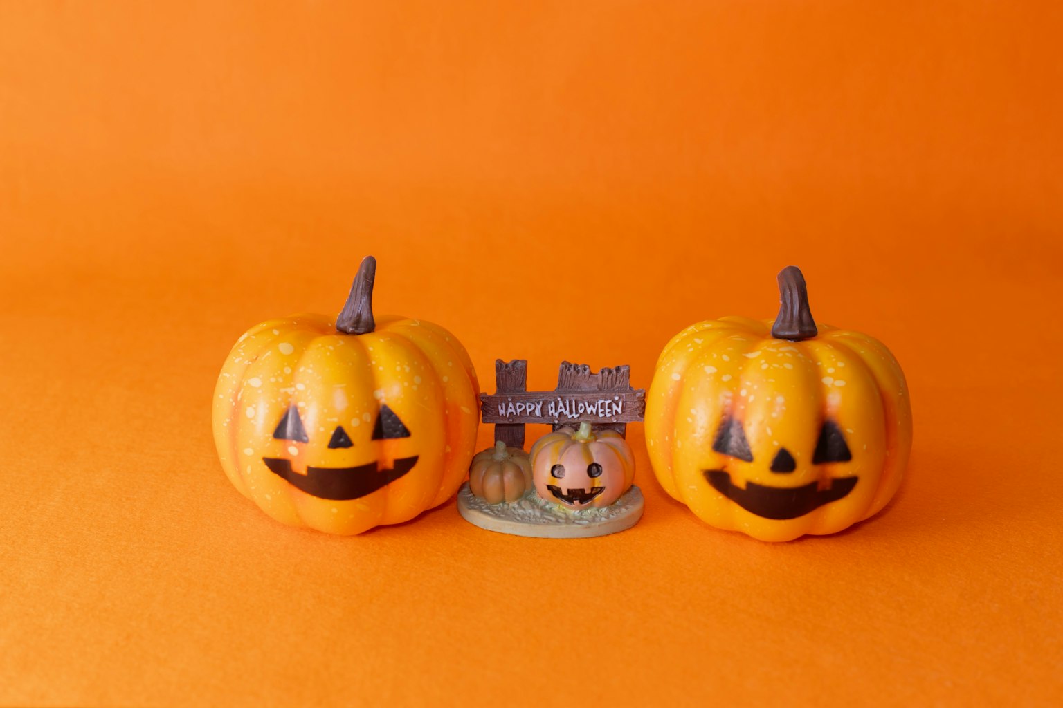 Due zucche jack-o'-lantern sorridenti con una piccola decorazione di castello su uno sfondo arancione