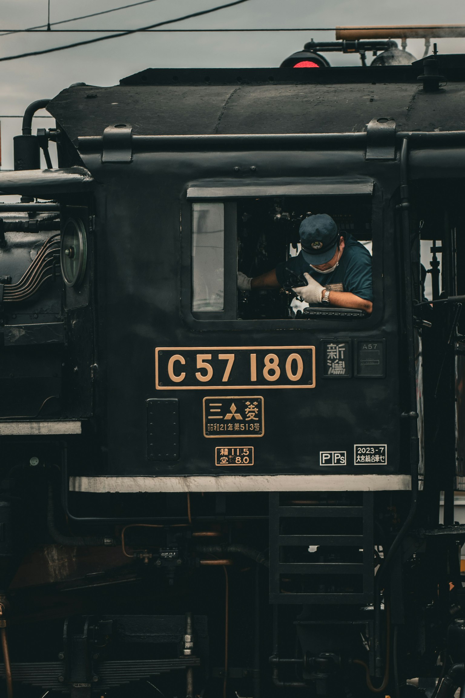 蒸気機関車の運転手が運転席にいる写真 C57180