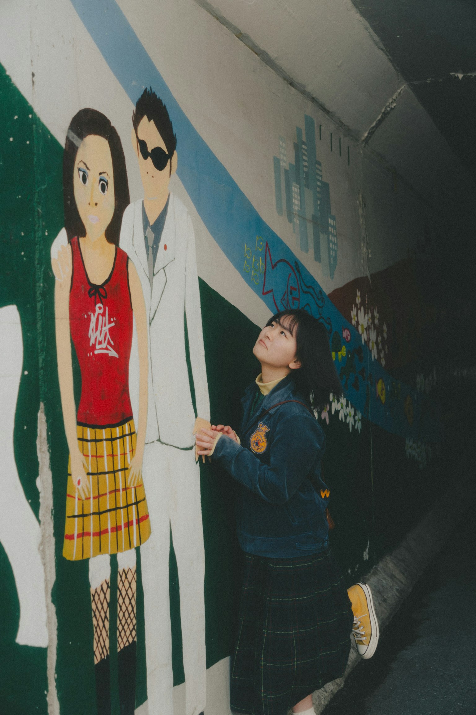 Ragazza che posa davanti a un murale con personaggi in stile anime