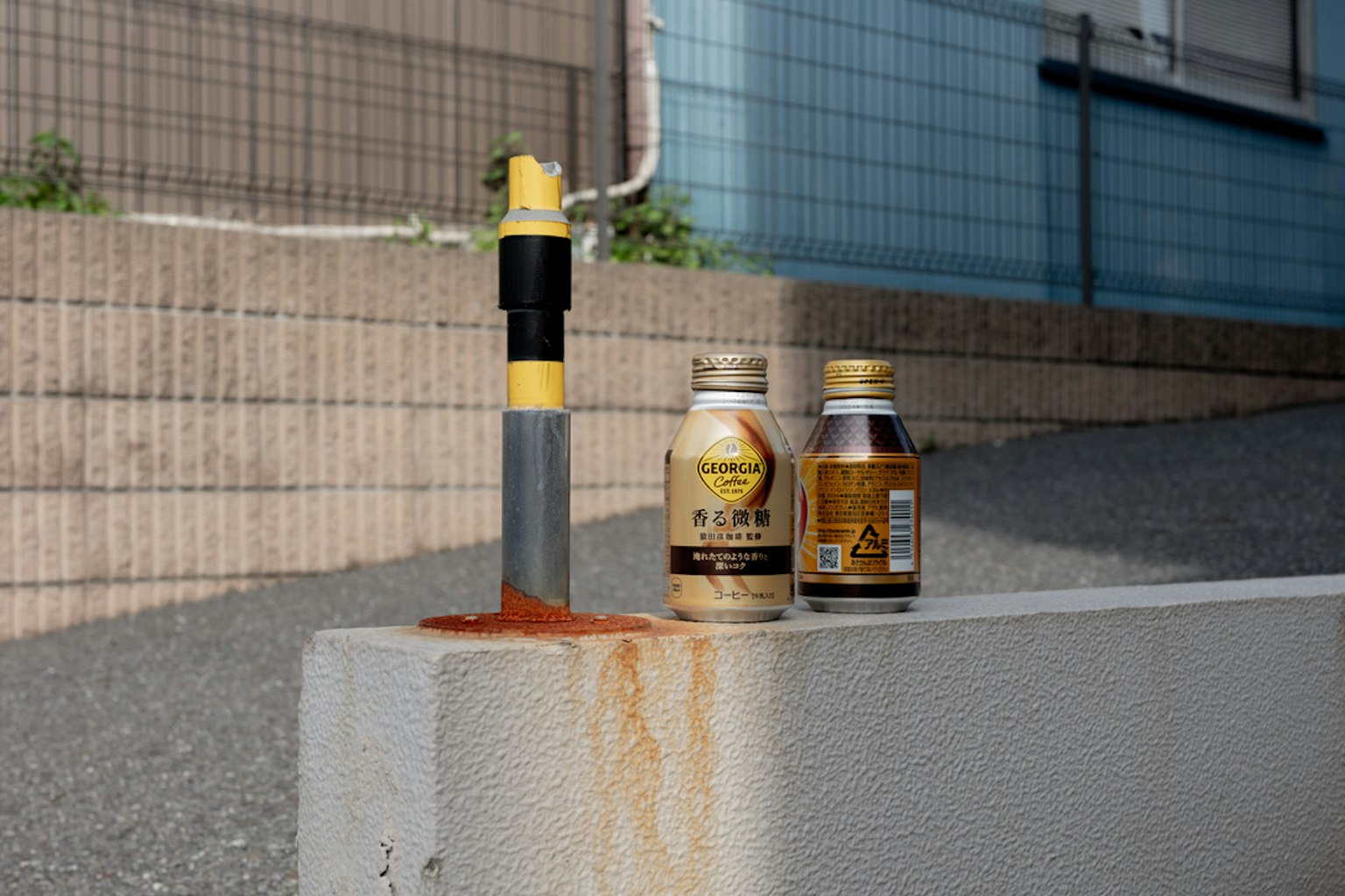 A concrete block with a yellow-taped pipe and two bottles beside it