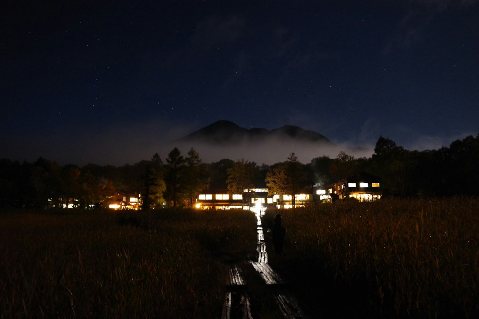 Luces de un alojamiento en un humedal de noche con cielo estrellado