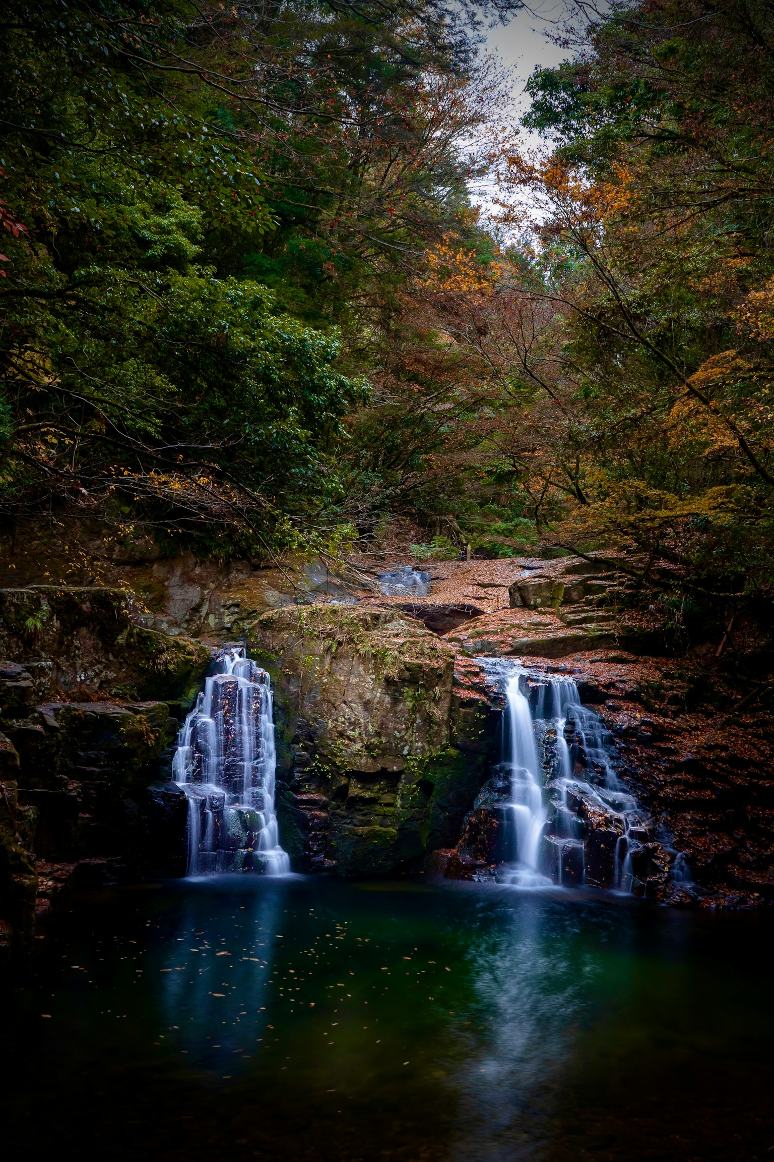 Vista escénica de cascadas gemelas rodeadas de follaje otoñal colorido