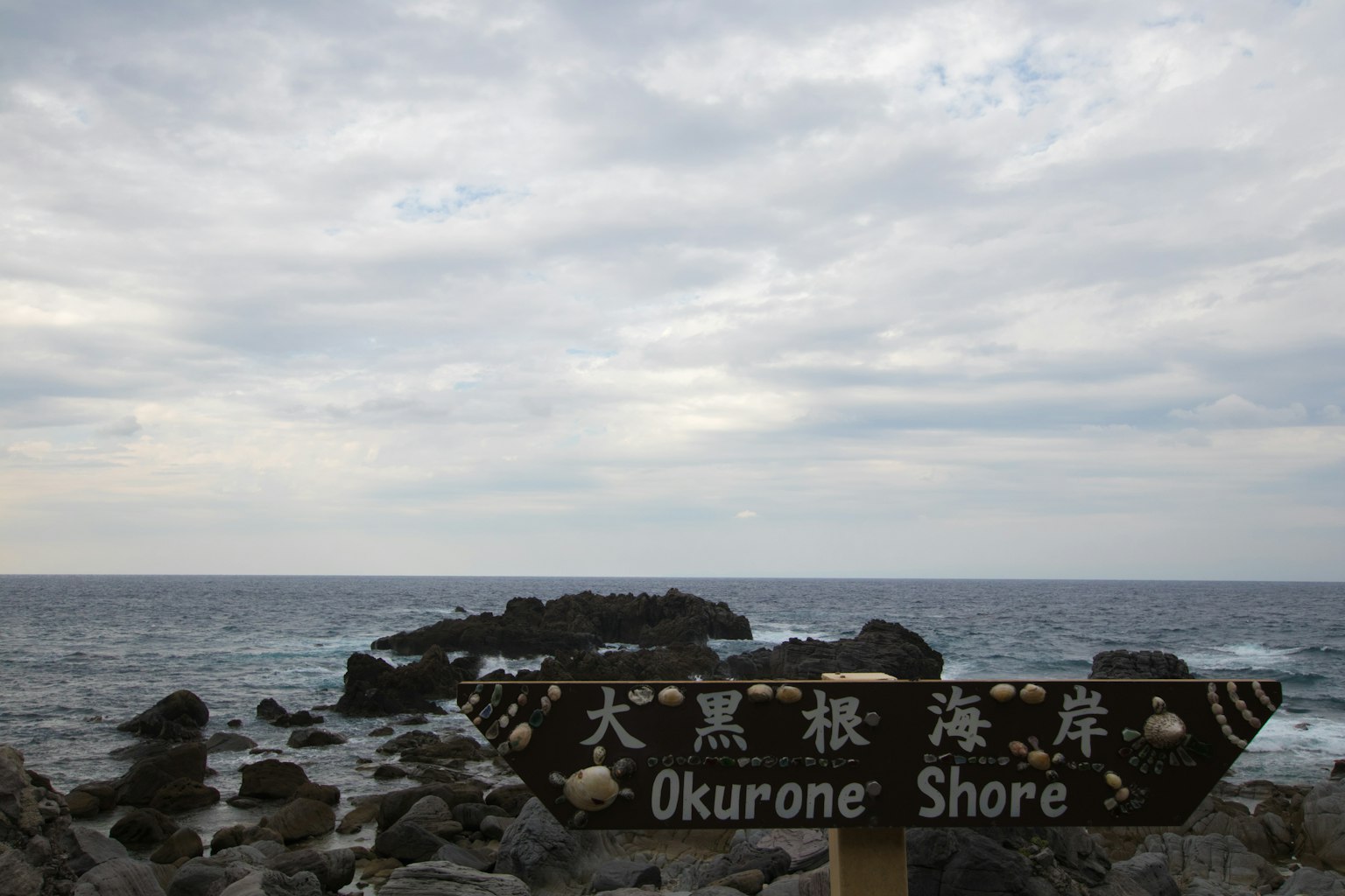 ทัศนียภาพของชายหาดโอคุโรเนะที่มีโขดหินขนาดใหญ่และท้องฟ้าครึ้ม