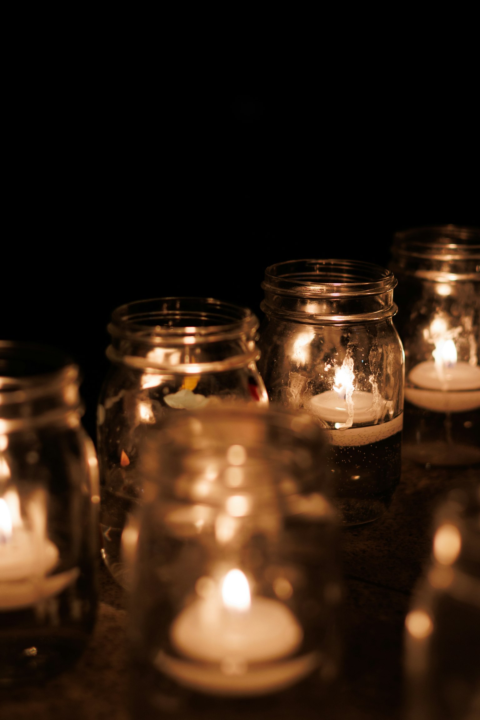 Bocaux en verre avec des bougies brillantes sur fond sombre